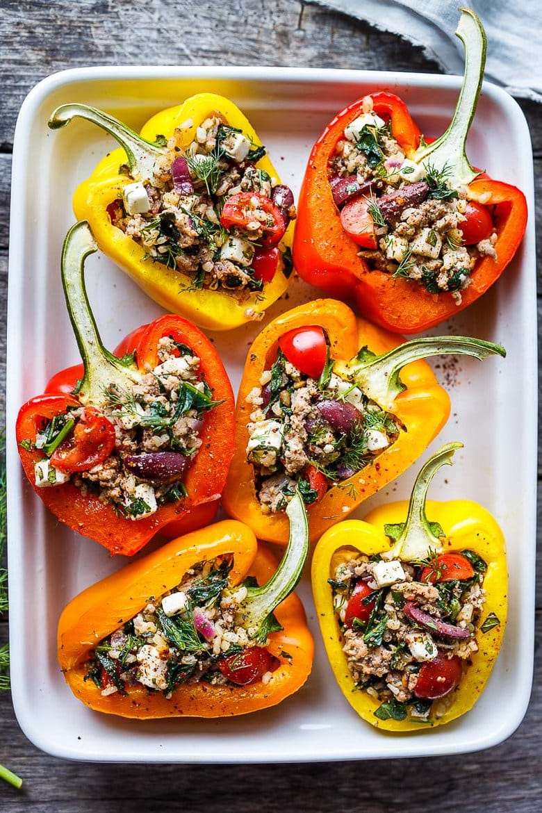 Mediterranean Stuffed Peppers with brown rice, ground turkey, tomatoes, olives, herbs, and feta in baking tray.
