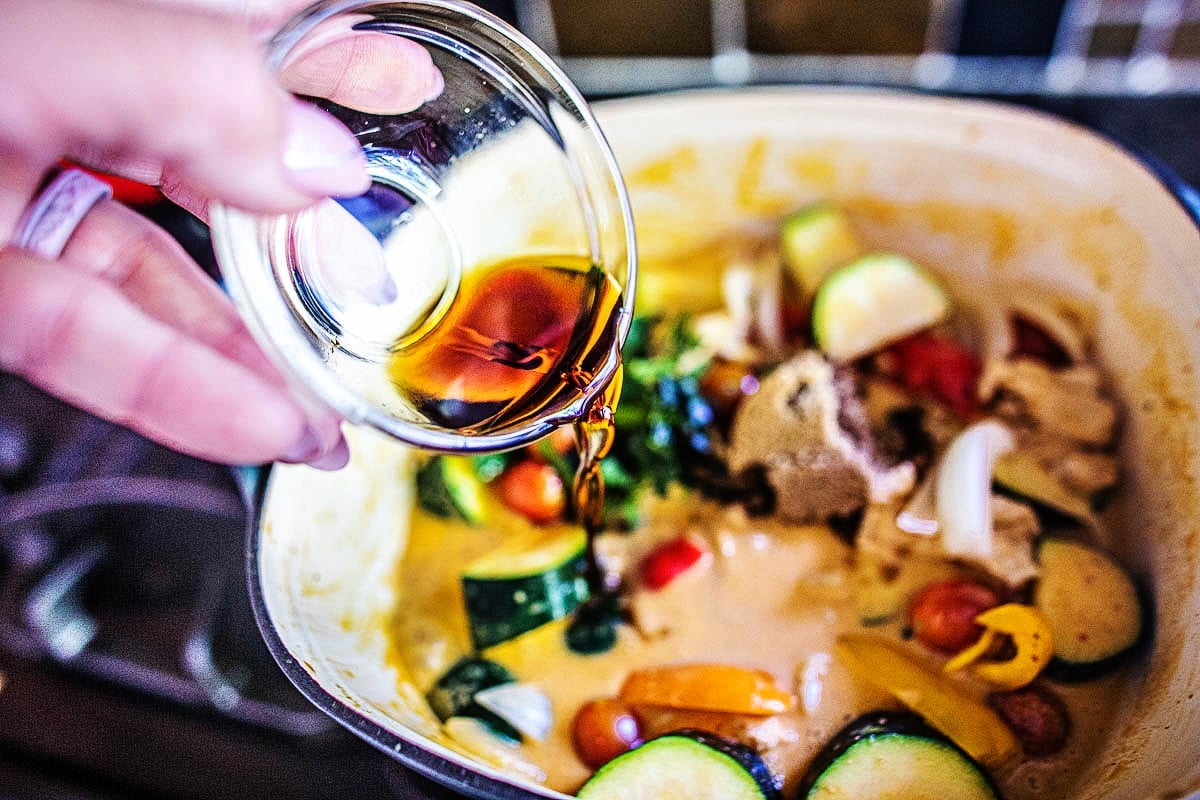 fish sauce added to a zucchini curry in a pot