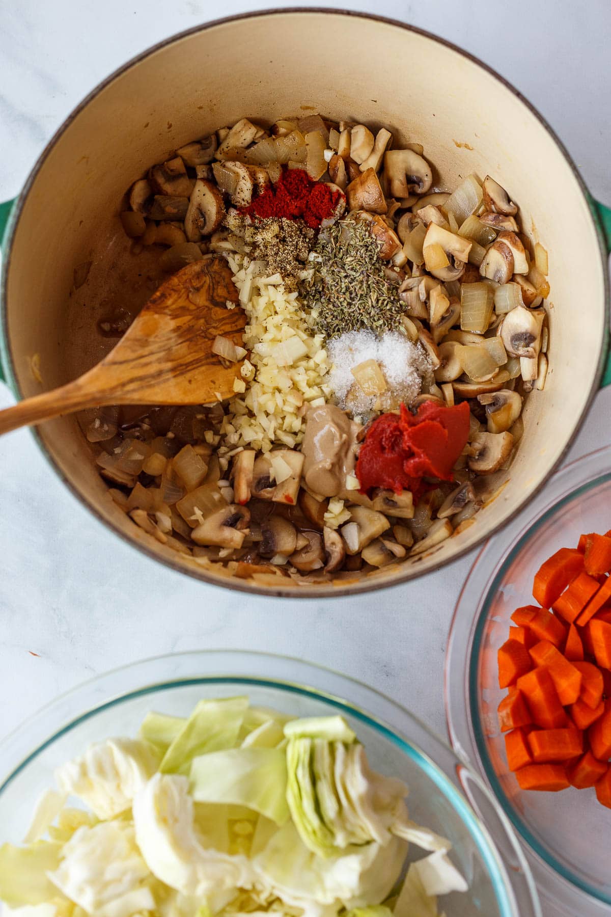 In a stock pot spices and tomato paste are added to mushrooms, cabbage and onions.