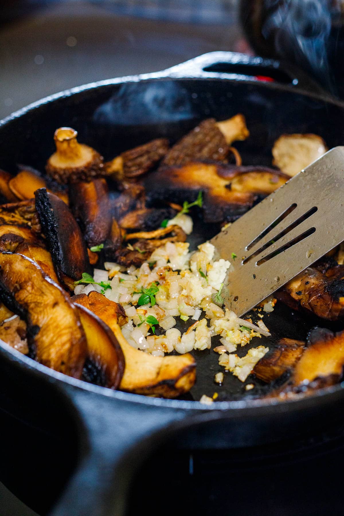 skillet with sautéed mushrooms, garlic, and shallots, with spatula.