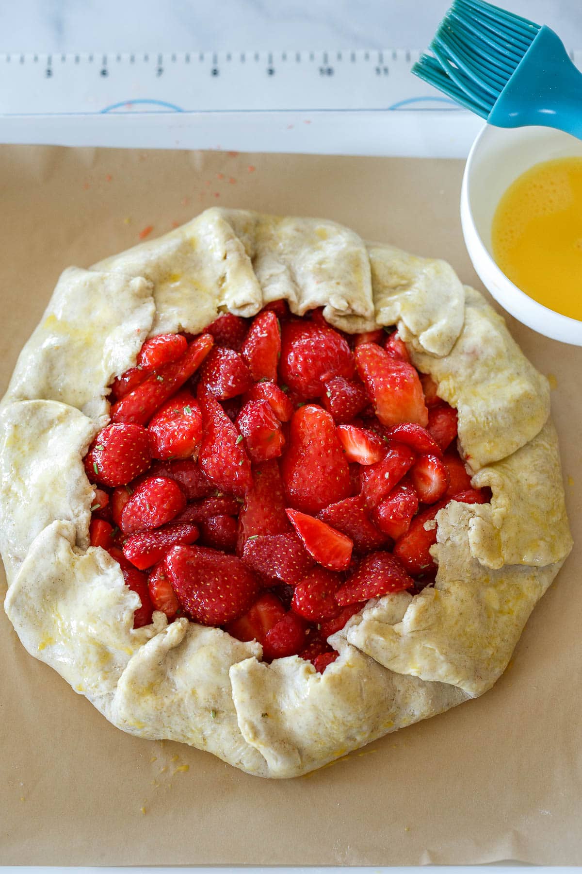 Strawberry filling with crust folded up around it and brushed with egg wash.