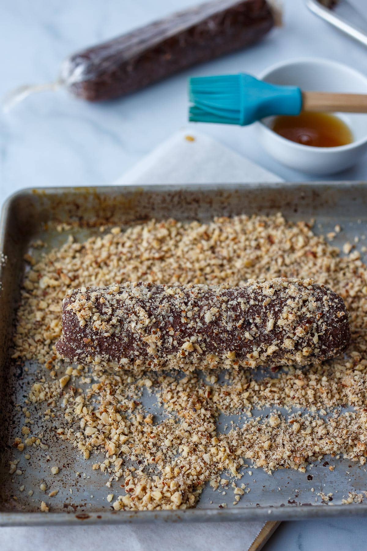 Rolling the cookie logs in ground hazelnuts.