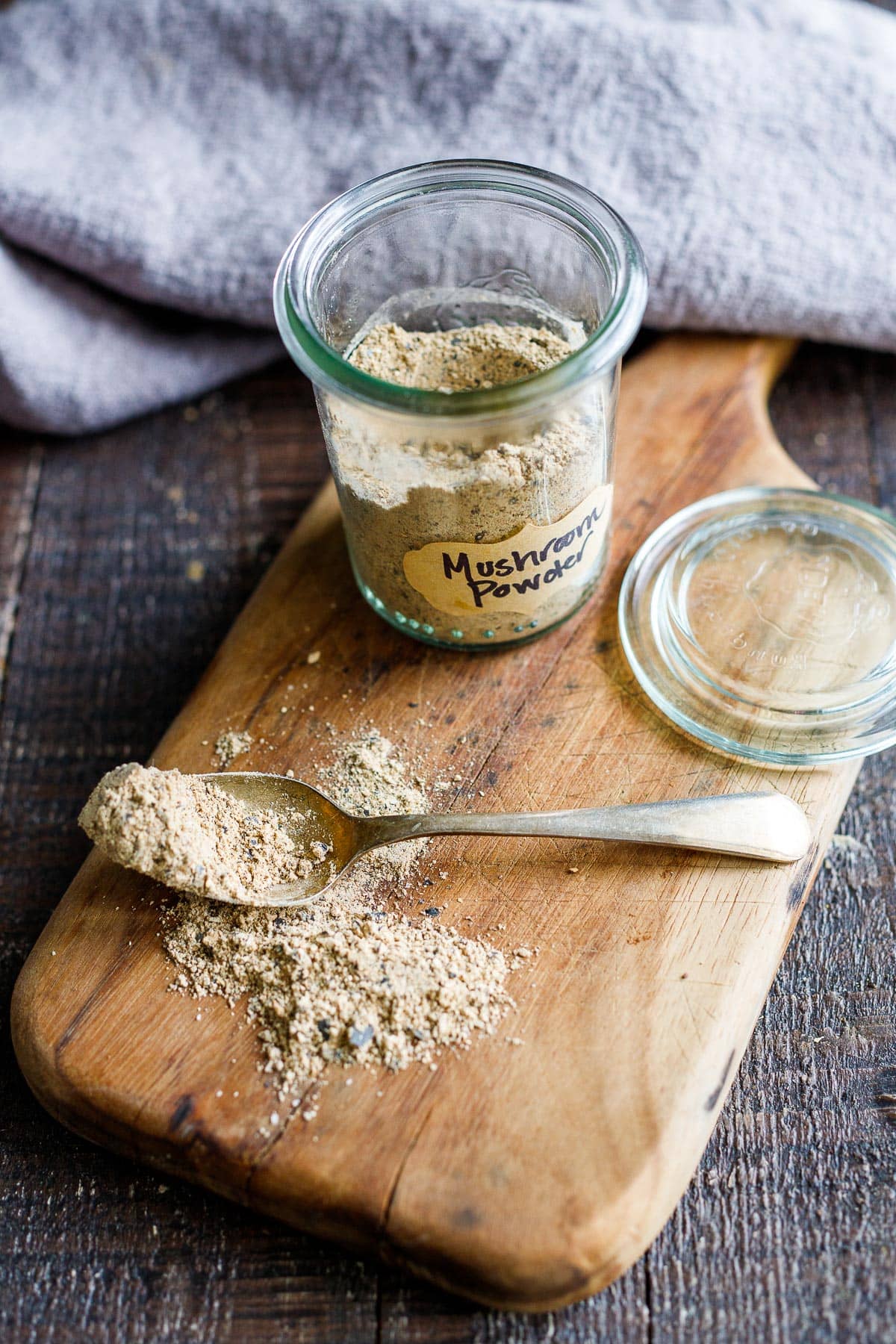 Mushroom powder on a cutting board with a spoonful of mushroom powder next to it.