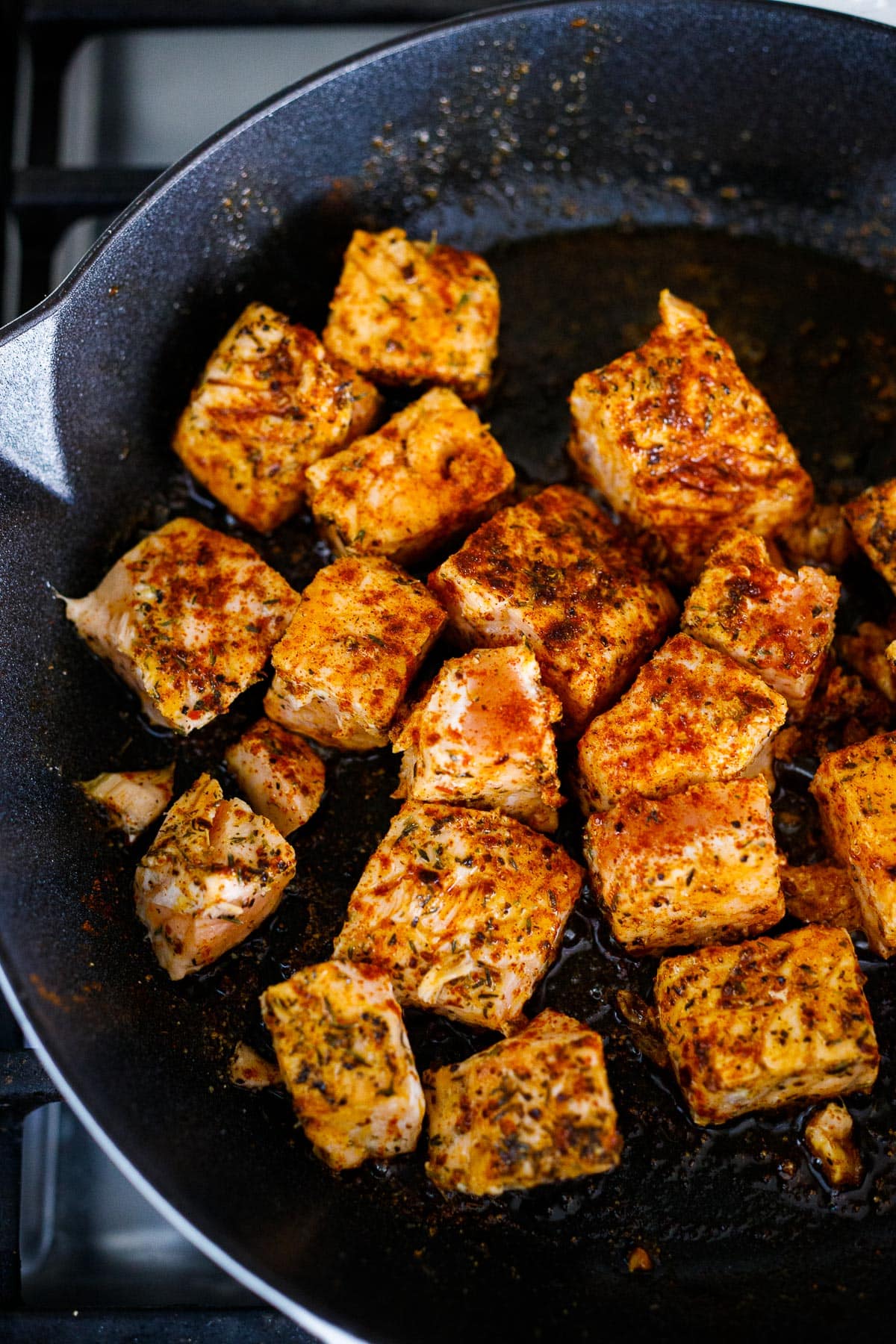 Salmon being seared in a skillet.