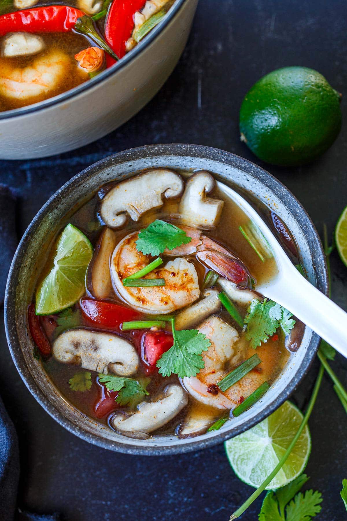 Tom yum soup in a bowl with shrimp and a spoon. 