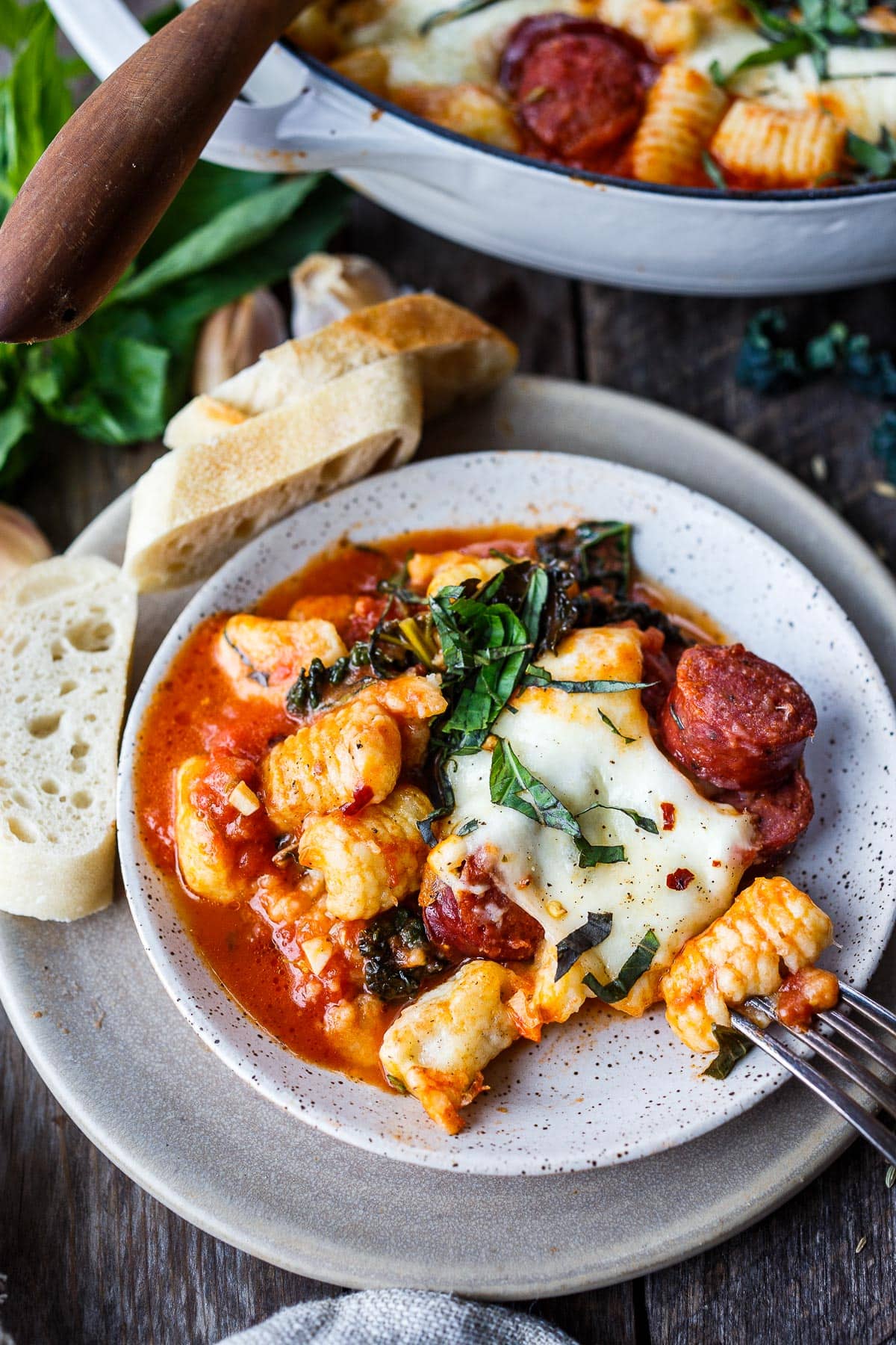 Baked gnocchi with tomato sauce, kale sausage and cheese served on a plate.
