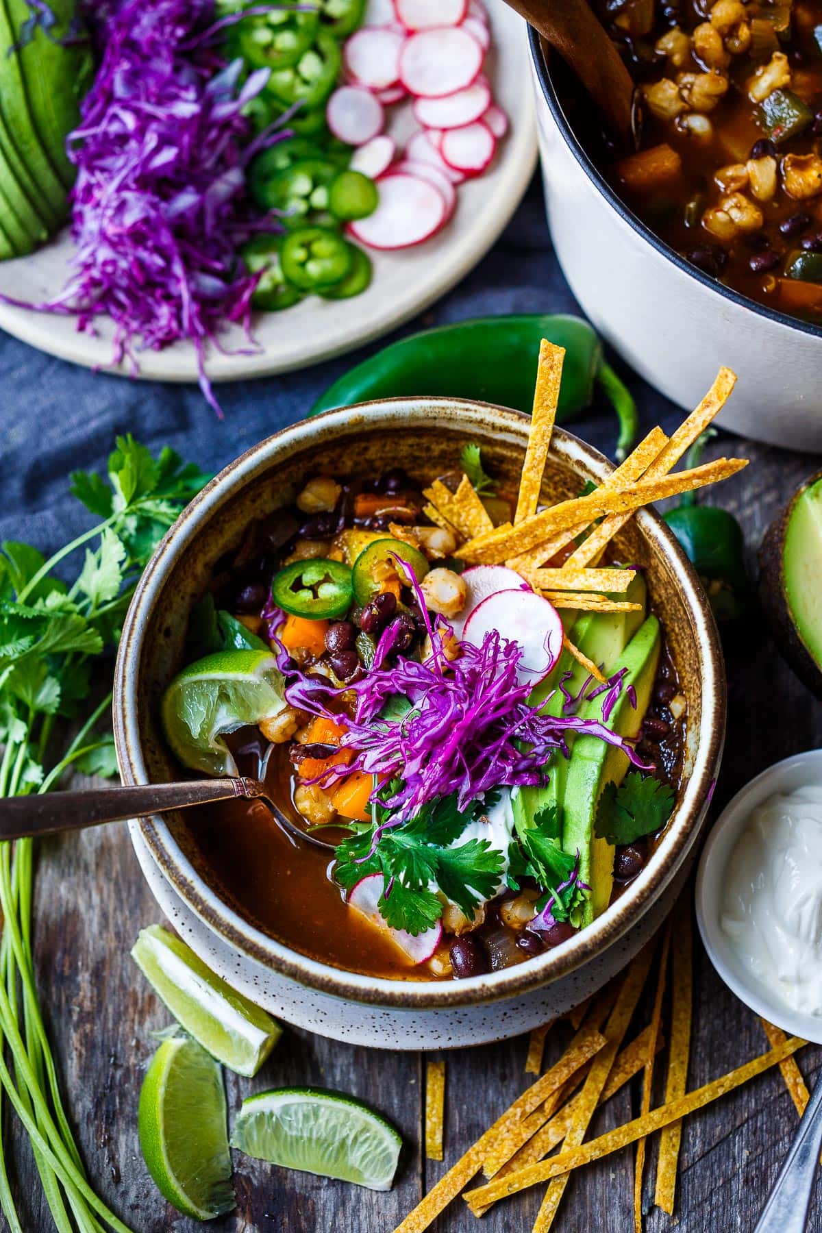 Colorful, veggie-loaded vegan pozole in a bowl with all the toppings.