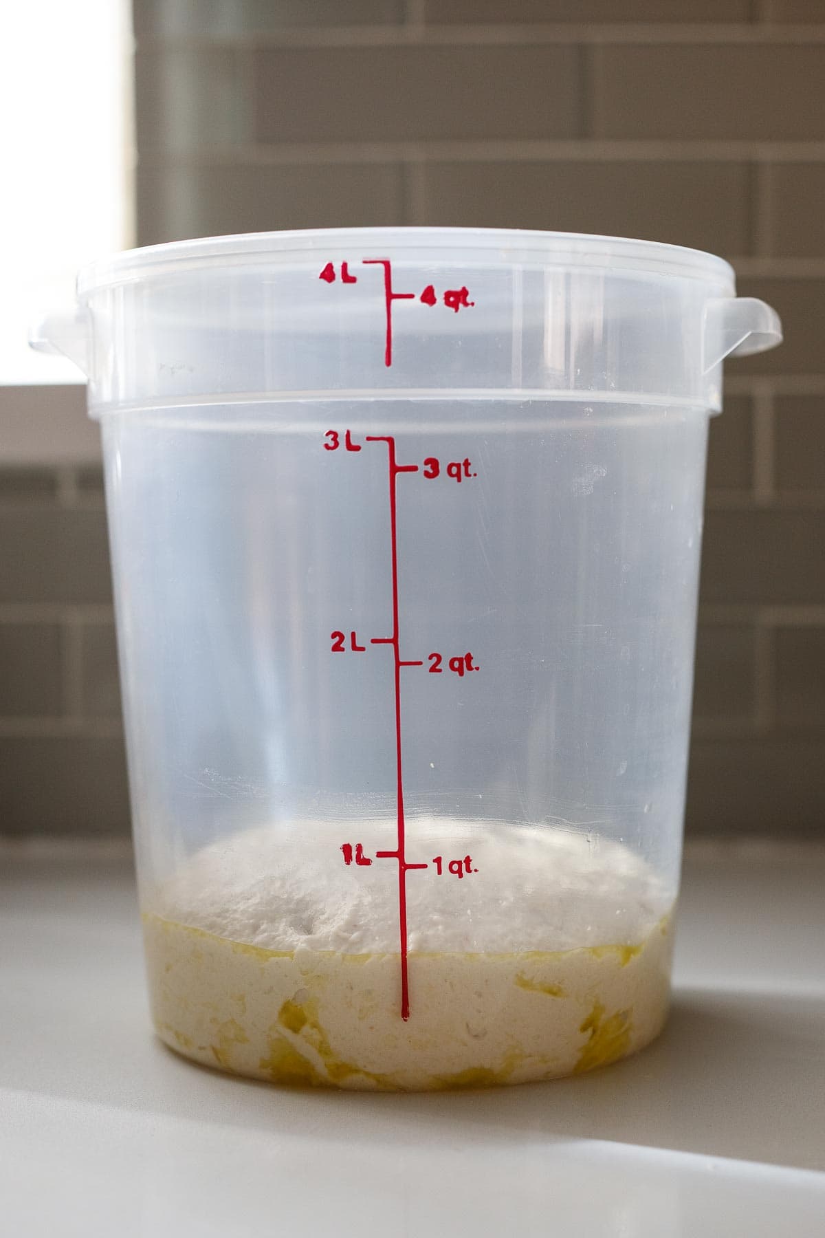 Storing the pizza dough in a tall sided container.