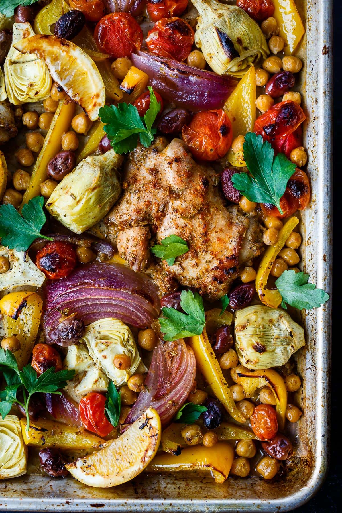 Mediterranean Chicken with veggies, chickpeas, olives and herbs. A delicious sheet pan dinner that is easy to make and easy to clean up!