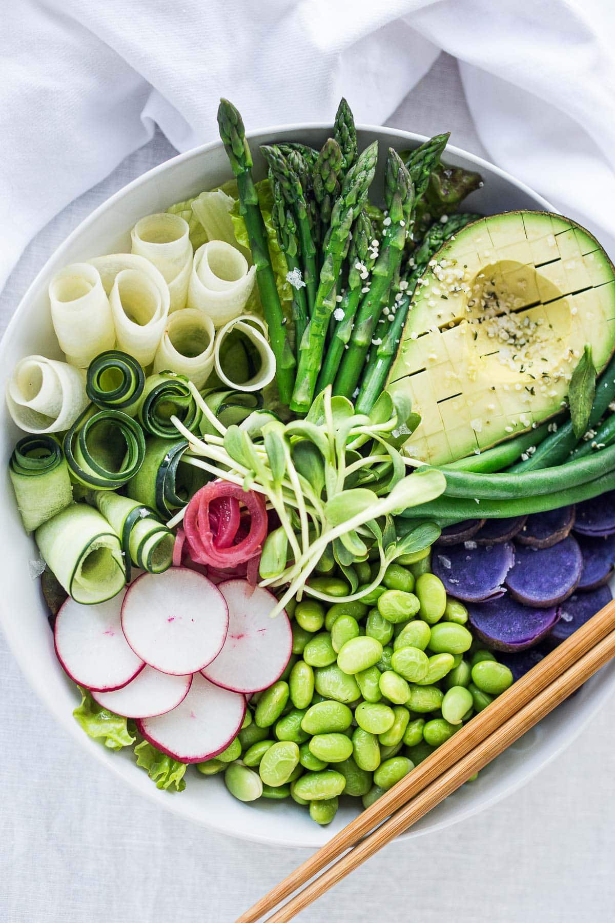 This Green Goddess Bowl features asparagus, green beans, avocado, edamame, purple potatoes and a vegan green goddess dressing. 