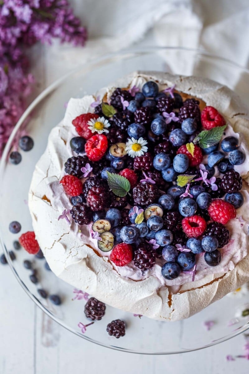 Pavlova with fresh berries and lofty whip cream. A light and airy dessert perfect for celebrations and gatherings. With a little planning ahead, this is easier than you may think!