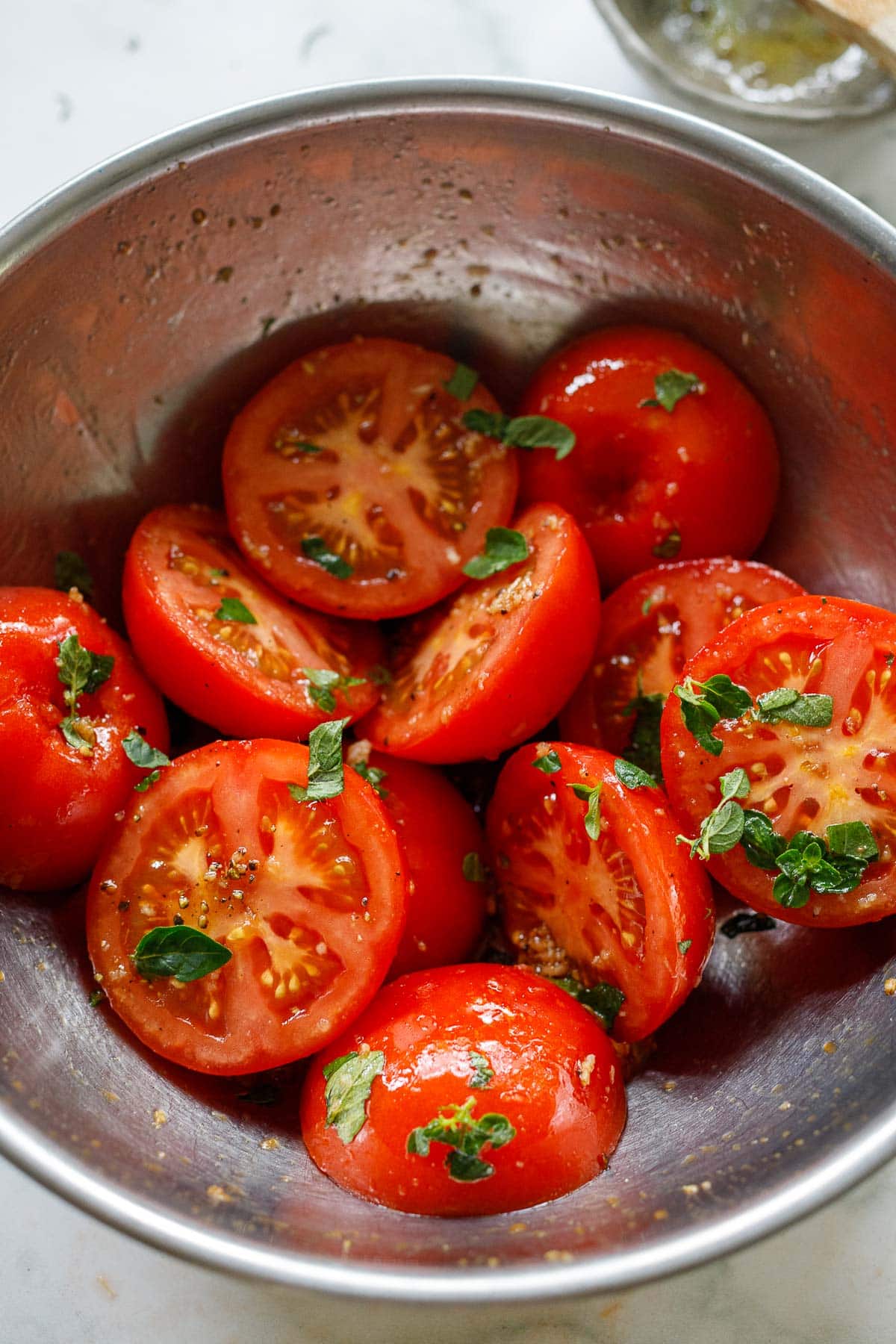 Tossing the halved tomatoes with the marinade in a bowl.