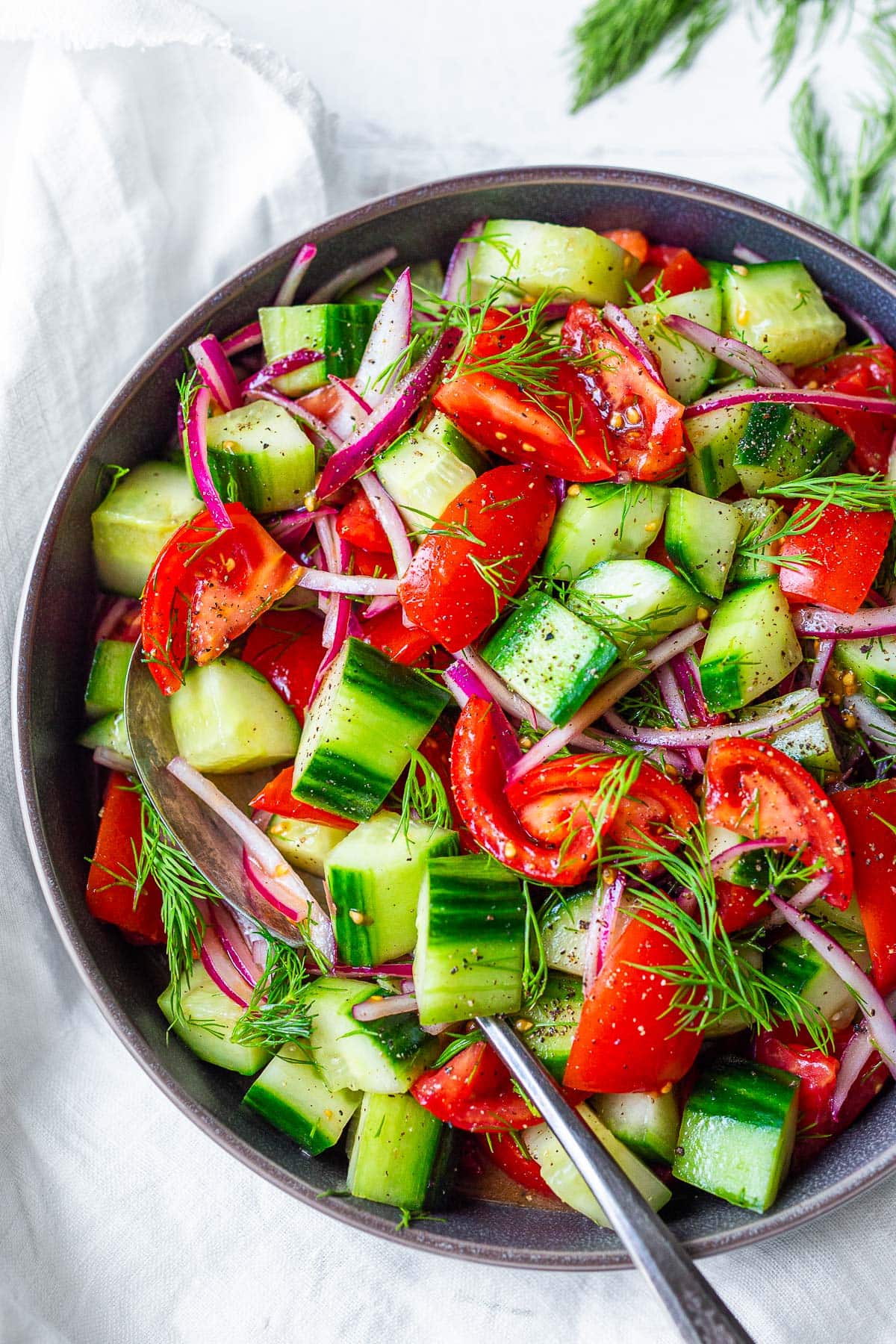Cucumber Tomato Salad in a grey bowl with dill and red wine vinaigrette.