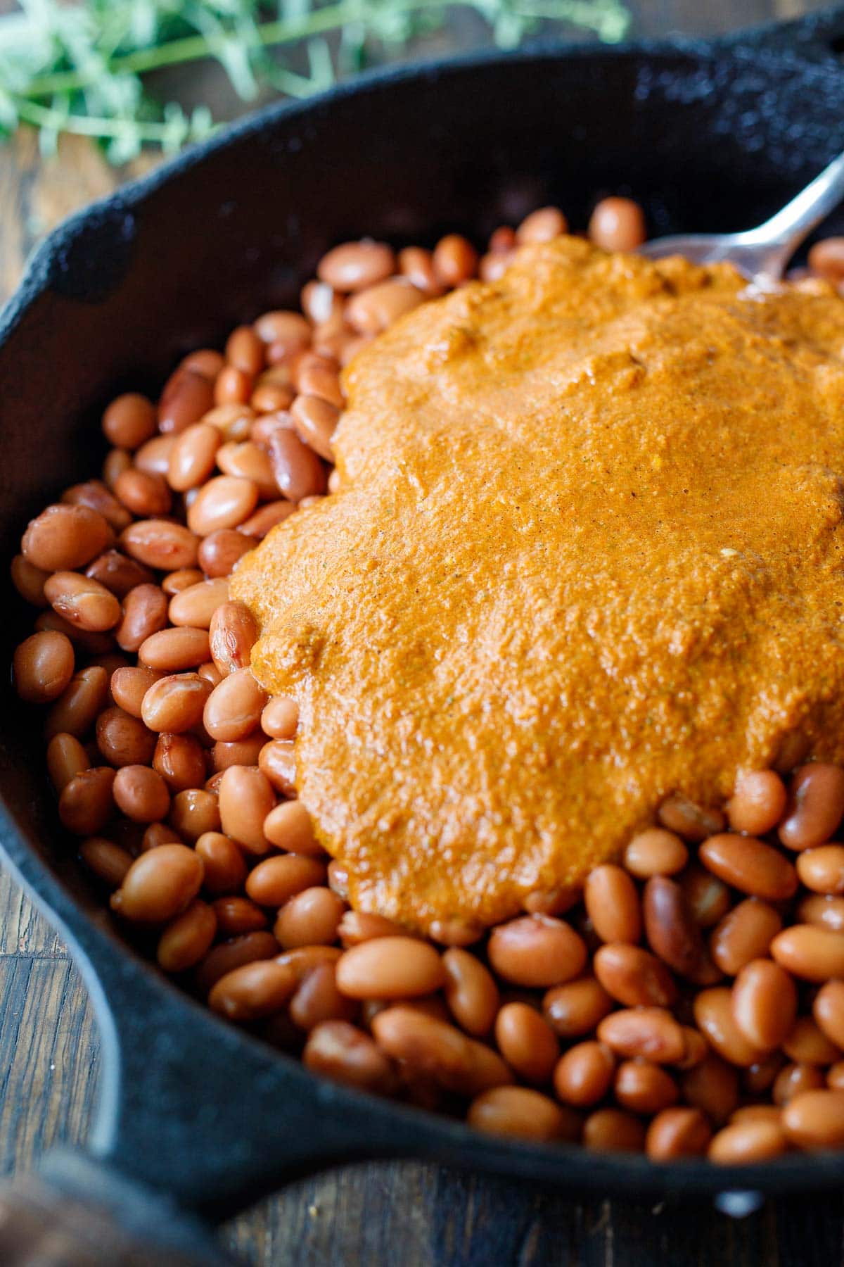 pouring enchilada sauce on the beans.