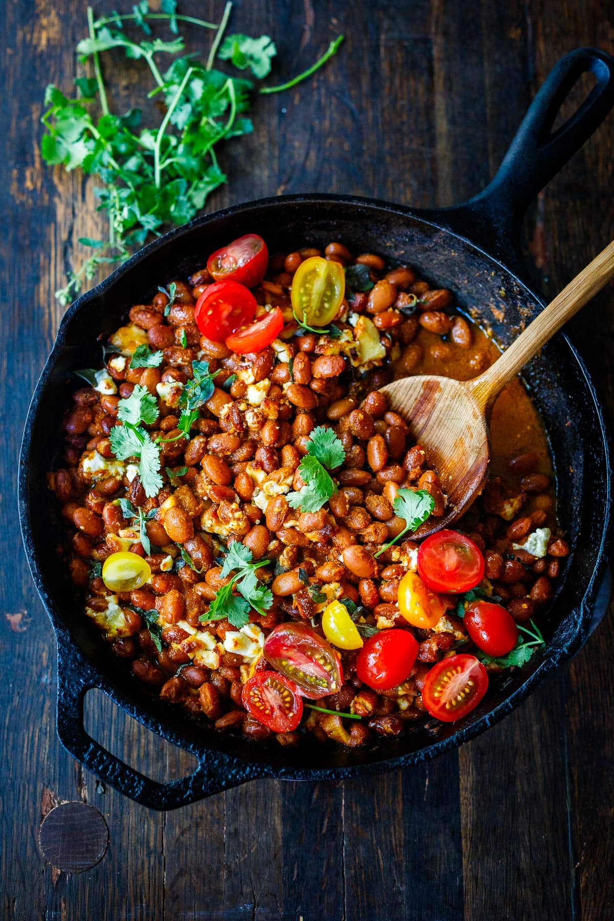 Baked pinto beans beans topped with tomatoes and cilantro