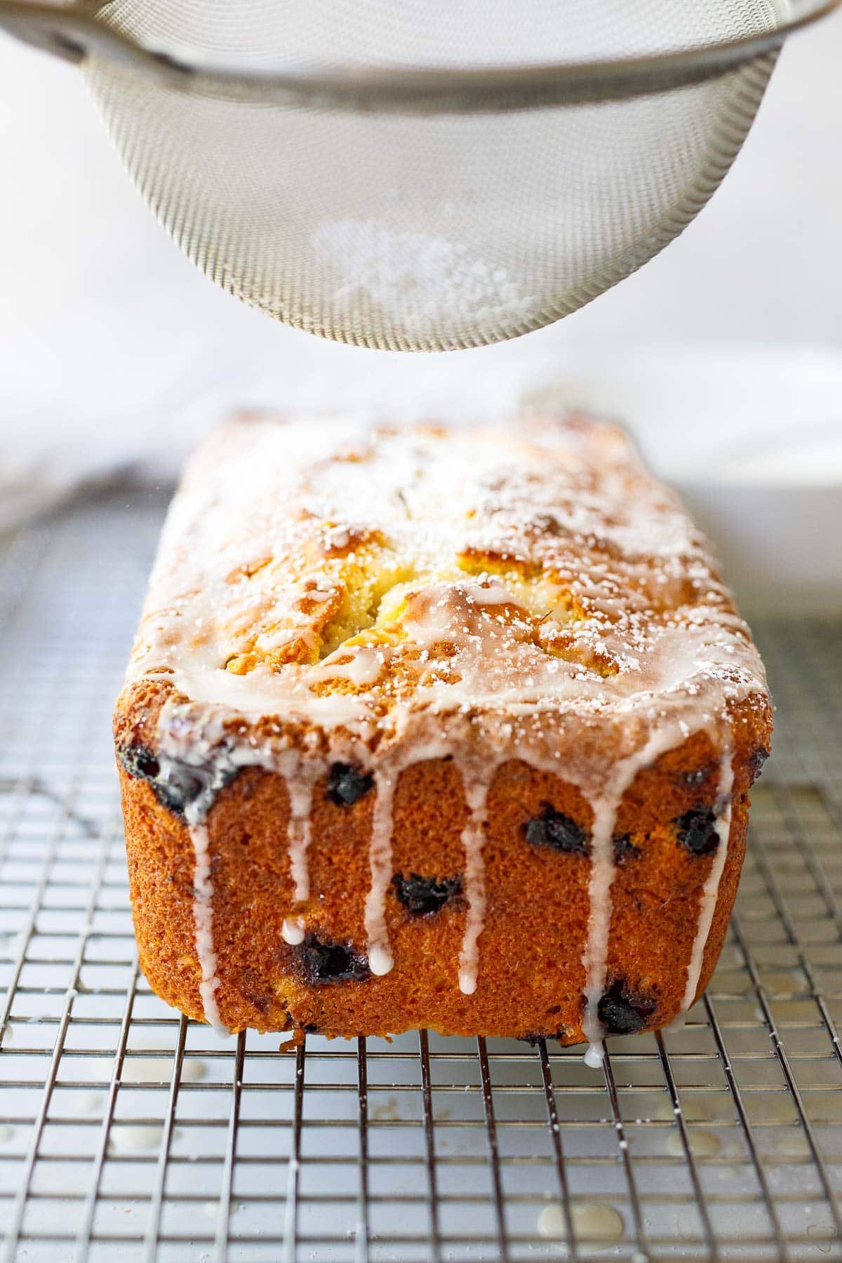 Sprinkling powdered sugar over the cake.