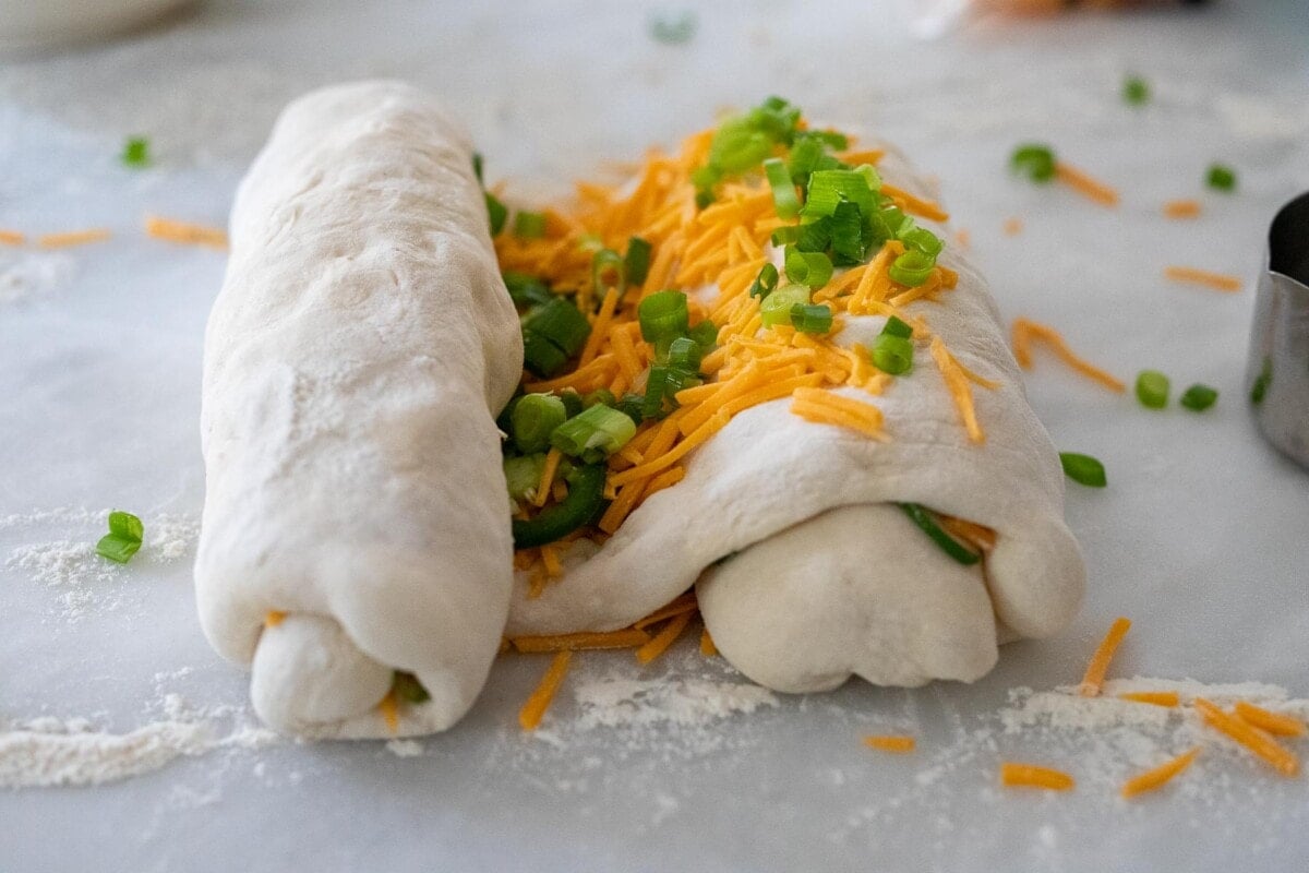 rolling dough into an "s" shape with cheddar and jalapeno on the inside.