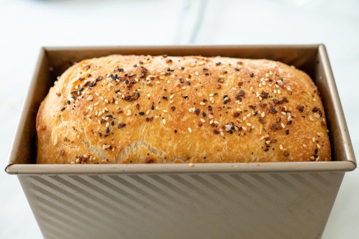 baked jalapeno cheddar sourdough in loaf pan with everything bagel seasoning.