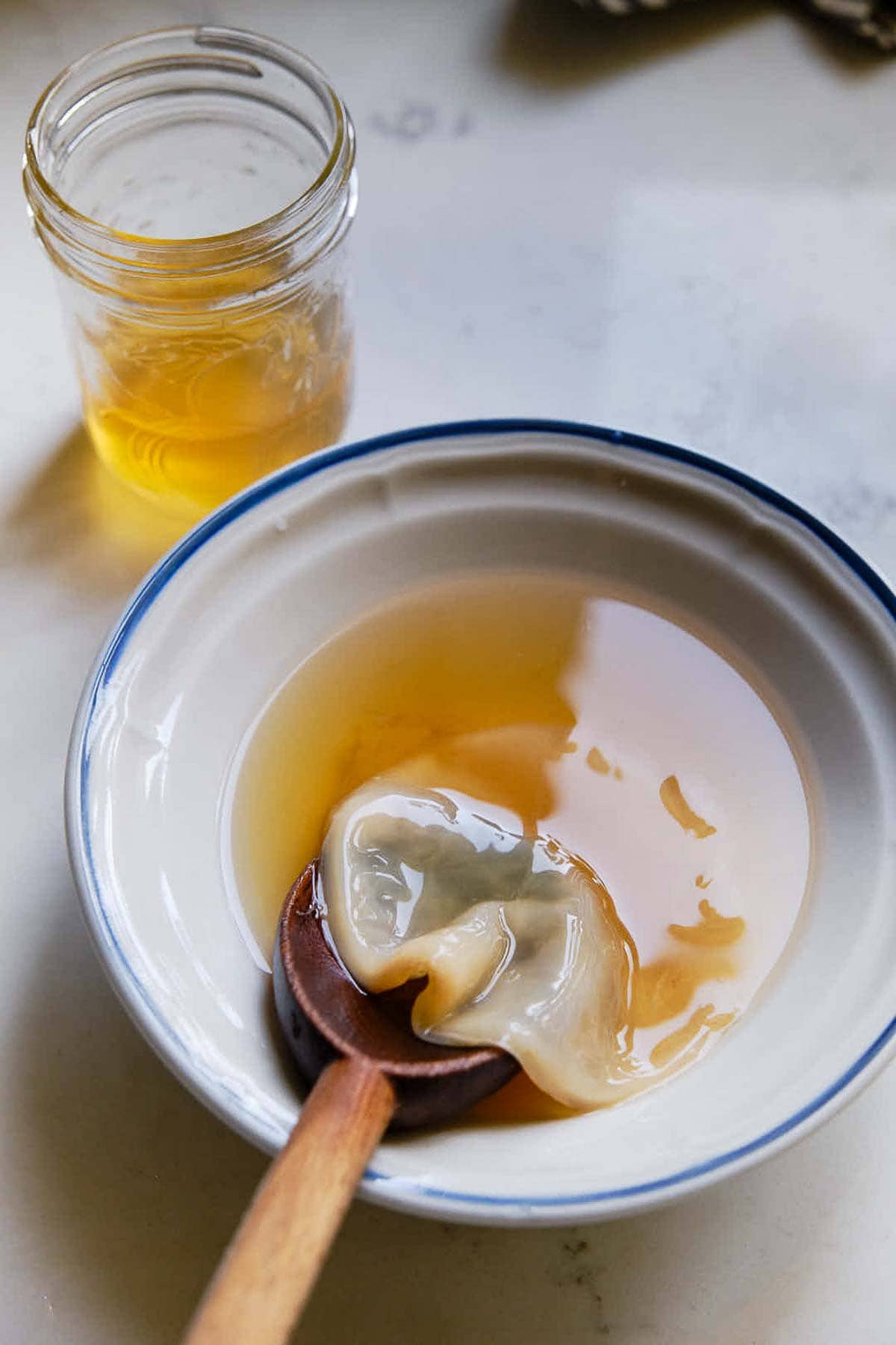 bowl with scoby and kombucha and wooden spoon.