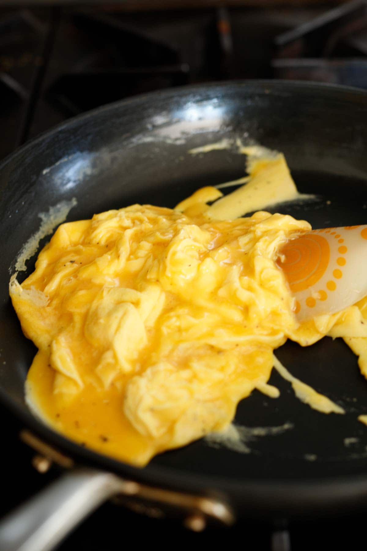 skillet with scrambled eggs, flipped with rubber spatula.