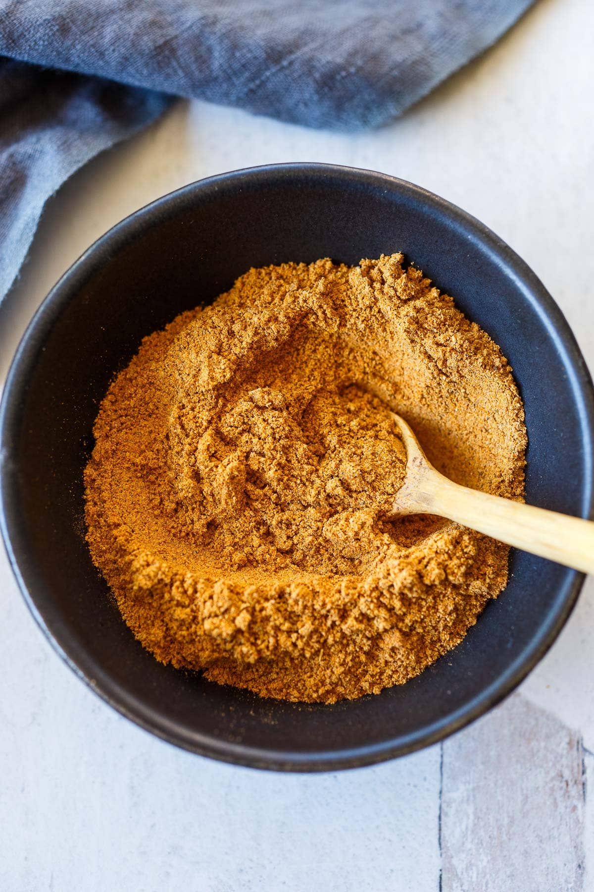 shawarma spice blended together with wood spoon in bowl.