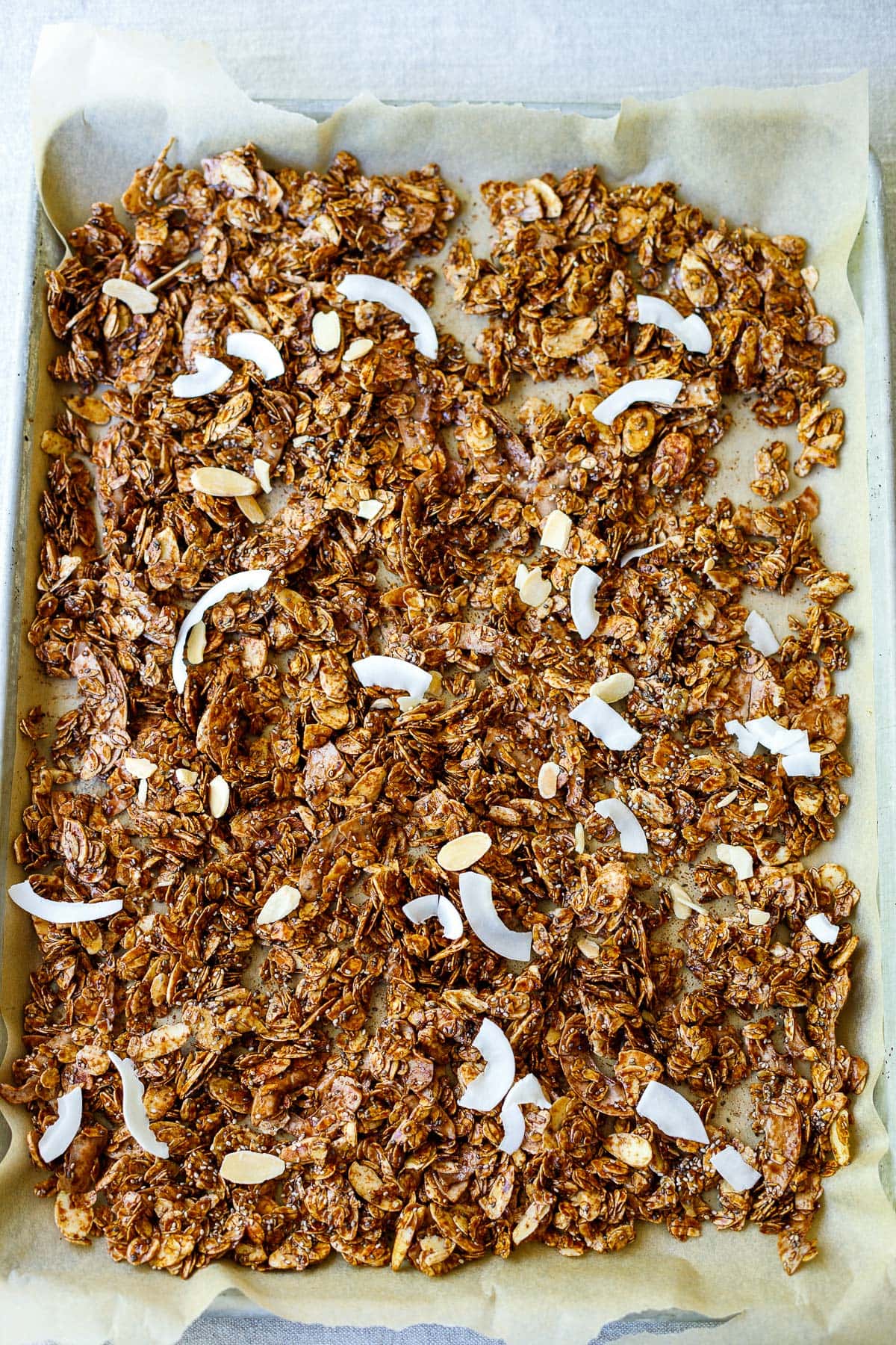 parchment-lined baking sheet with unbaked dark chocolate granola ingredients spread out.