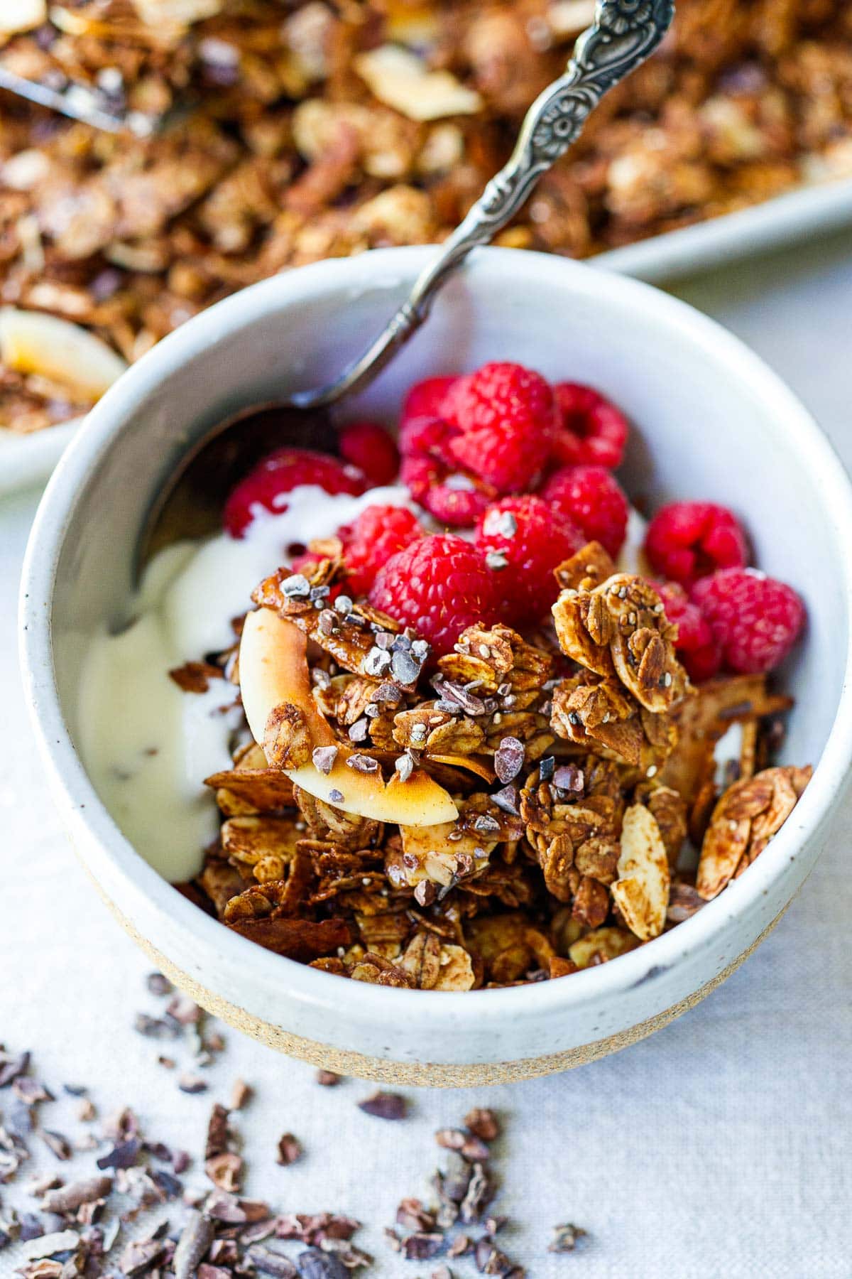 small bowl of yogurt and raspberries with dark chocolate granola on top.