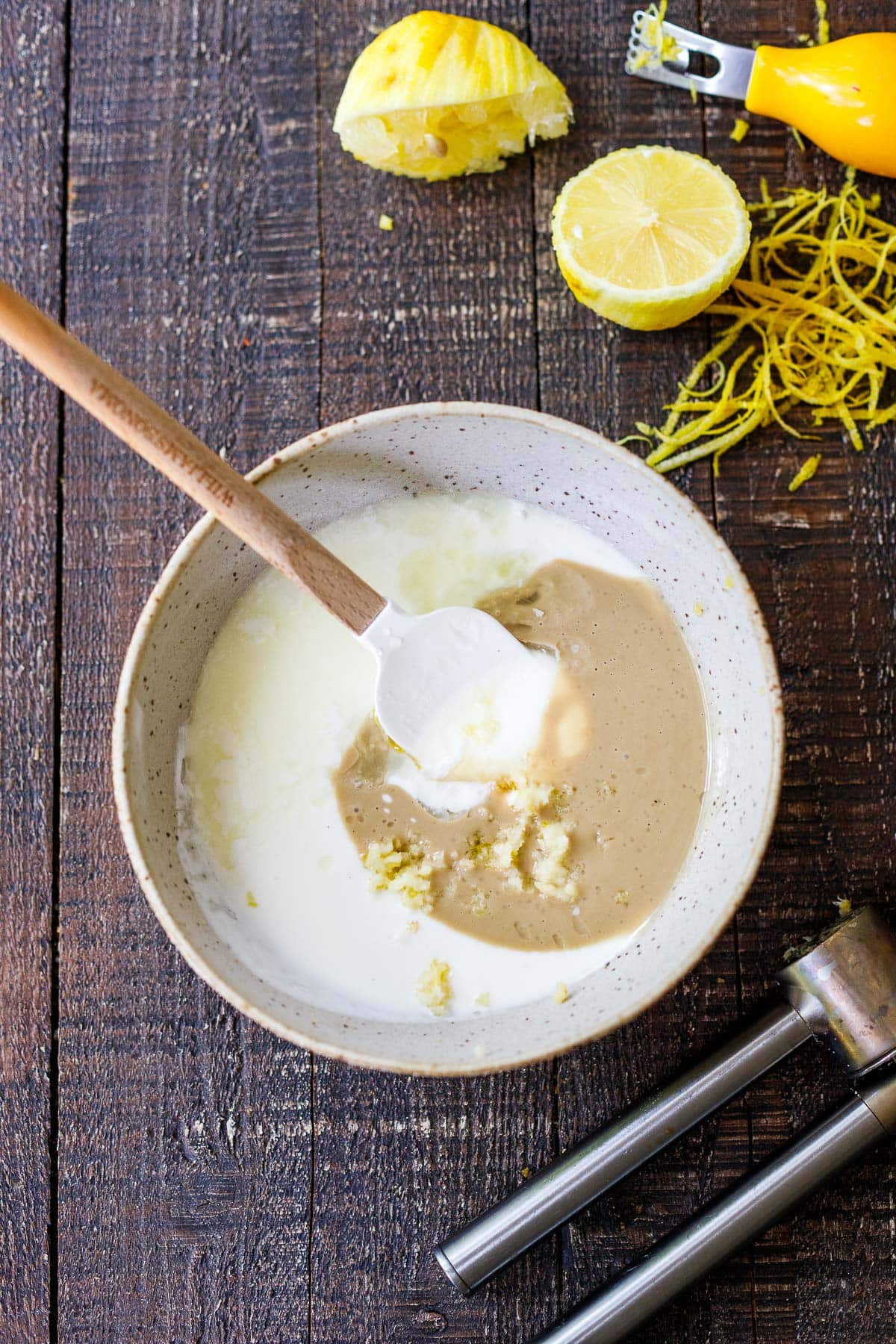 spatula stirring together yogurt tahini sauce in bowl. 