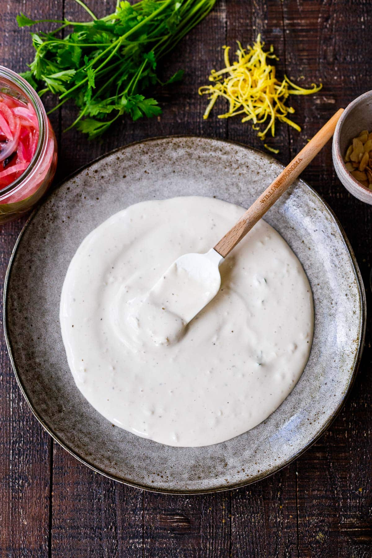 plate with spatula spreading yogurt tahini sauce over top. 
