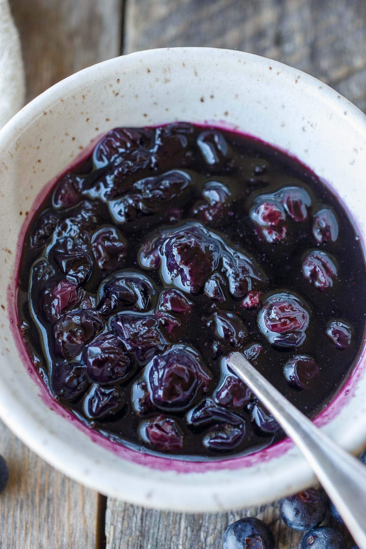 small bowl with blueberry maple syrup with whole, wilted berries. 