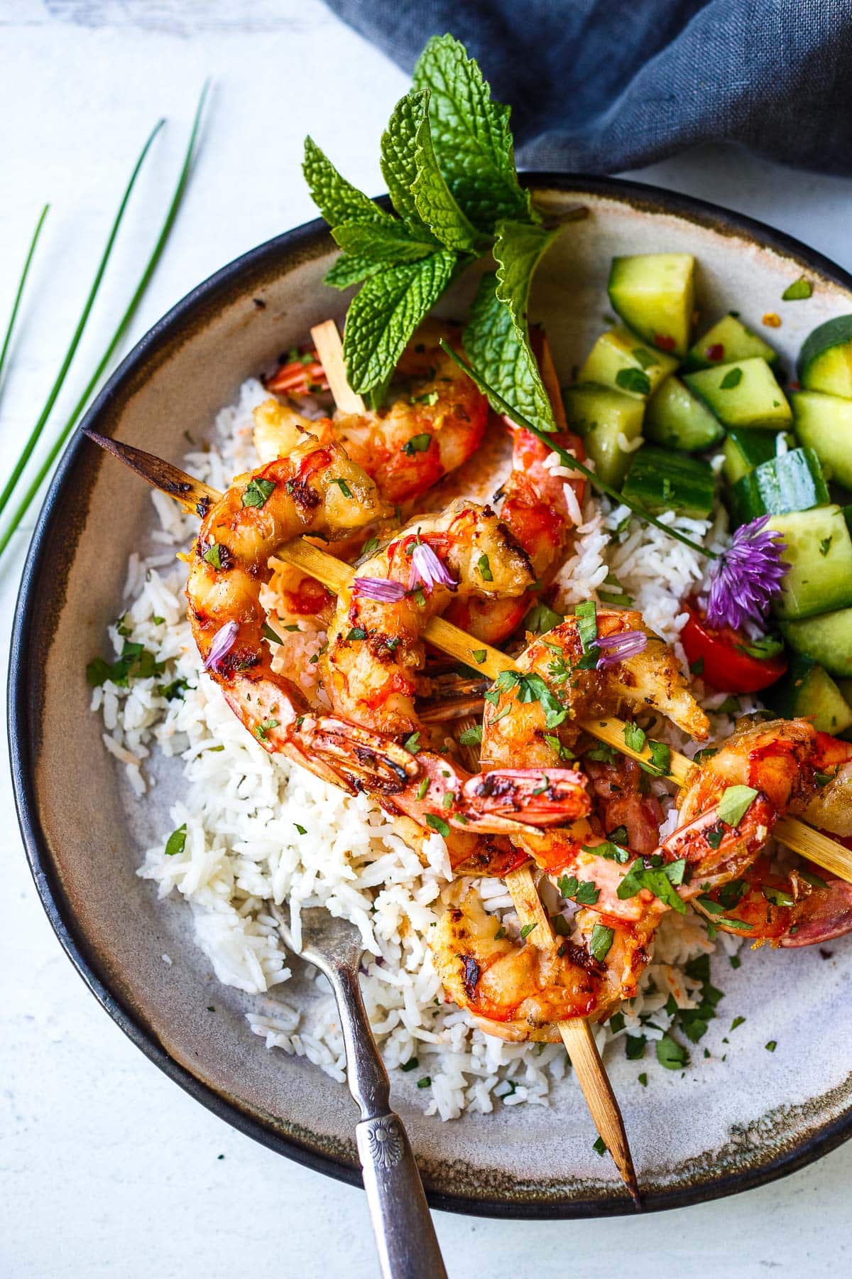 bowl with coconut rice, cucumbers, and grilled lemongrass shrimp skewers.