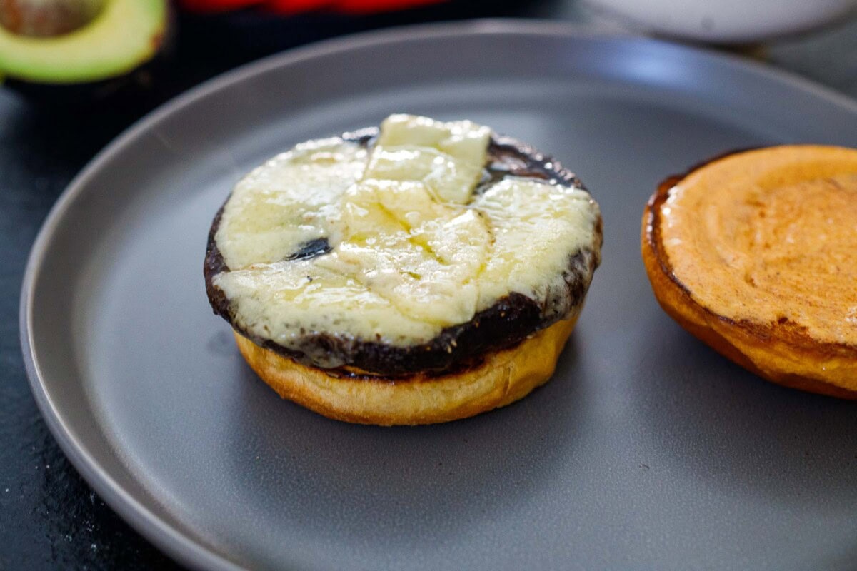 plate with toasted brioche buns, one with chipotle mayo on top, and the other with roasted portobello and melted cheese.