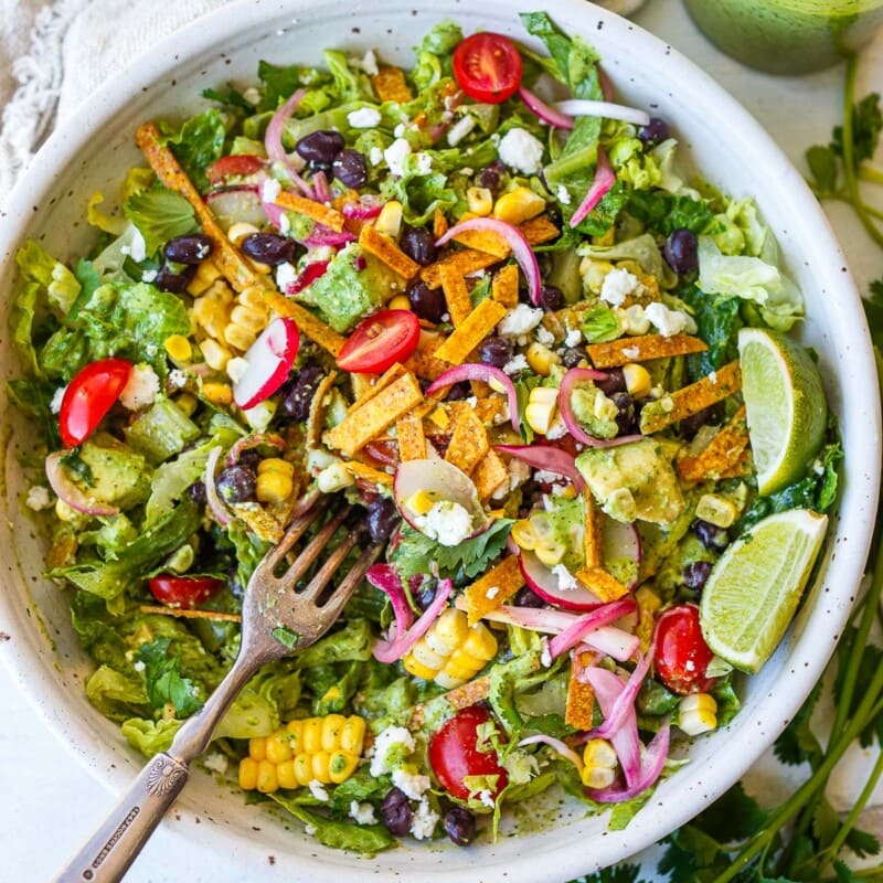 This vegetarian Taco Salad recipe is so tasty! It's easy and flavorful, made with black beans, tomatoes, avocado, and crisp romaine with a zesty, creamy cilantro lime dressing. Gluten-free and vegan-adaptable.