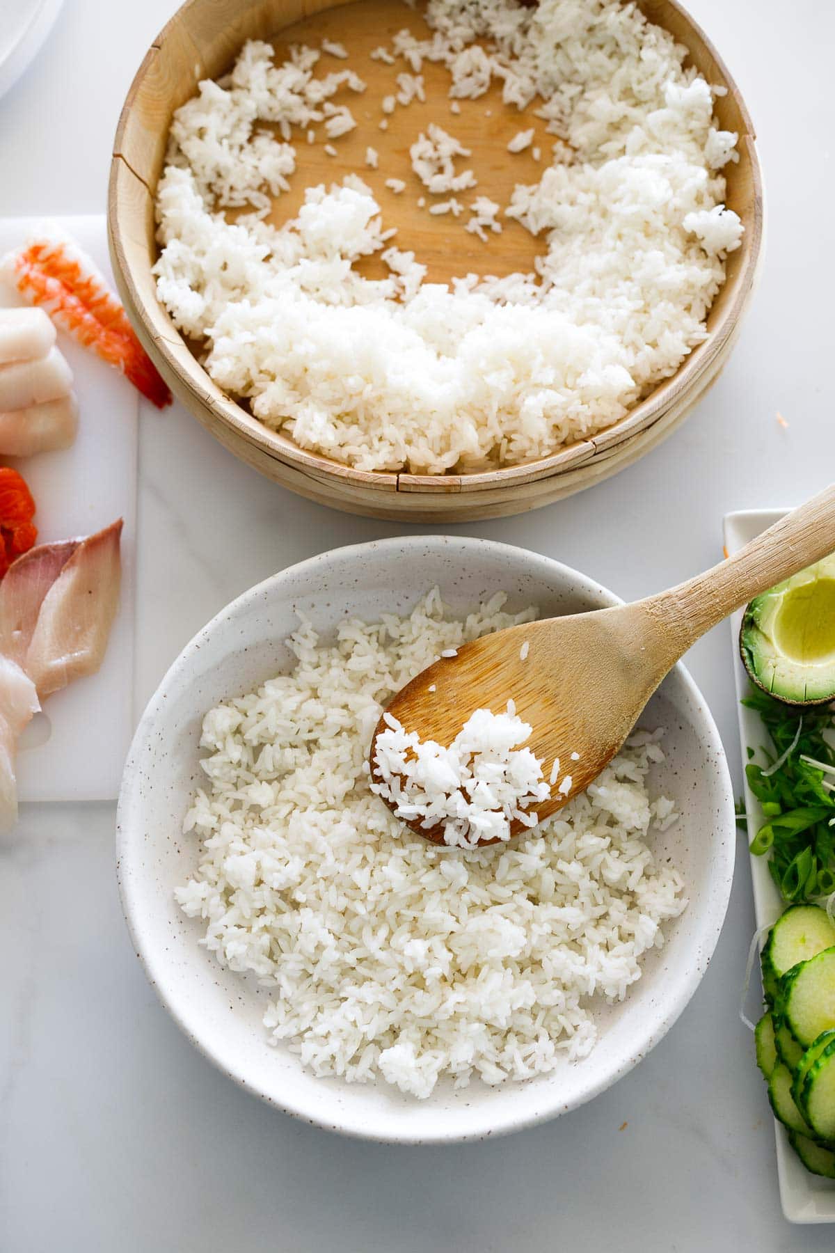 wood bowl with sushi rice next to bowl of sushi rice with wood spoon.