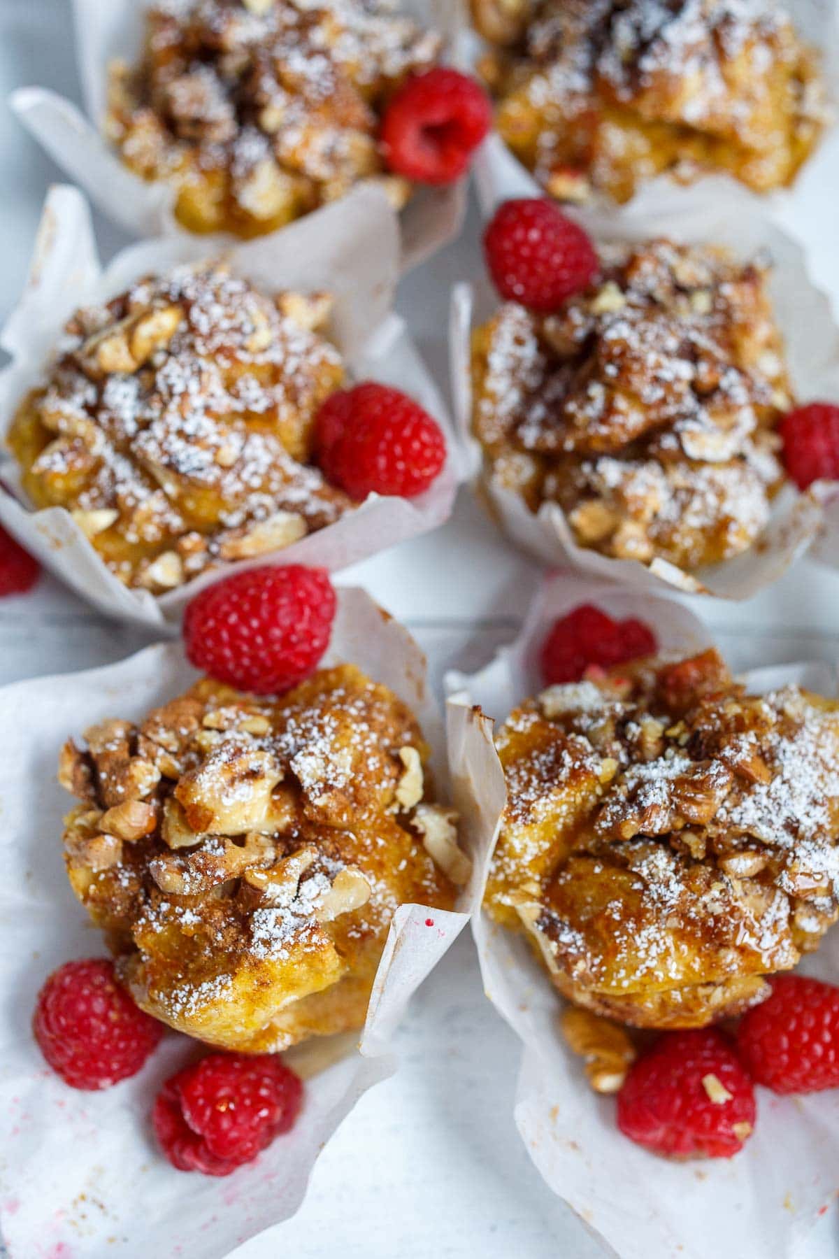 baked French toast muffins topped with powdered sugar and raspberries.