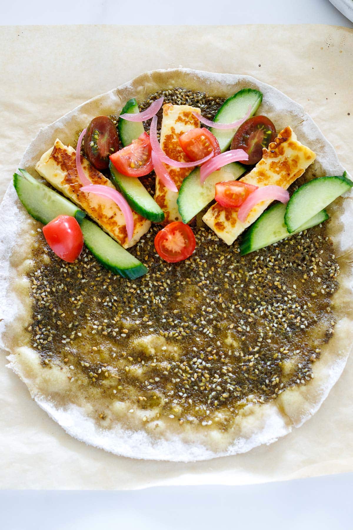manoushe with zaatar paste, and half the wrap topped with cucumber, tomato, pickled onions and pan-seared halloumi cheese.