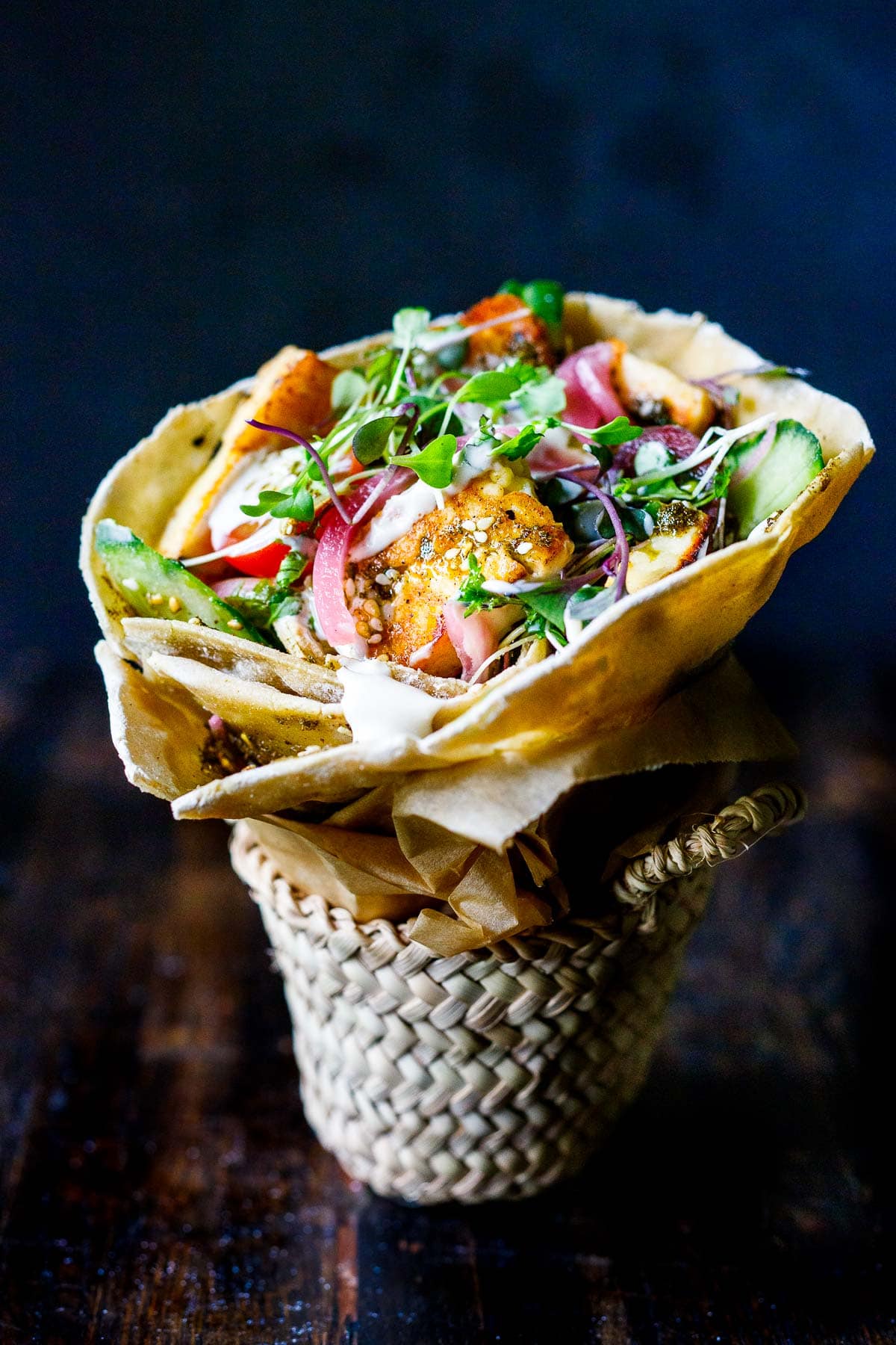 halloumi wrap with pickled red onions, micro greens, and pan-seared halloumi in manoushe, wrapped like a cone in small basket.