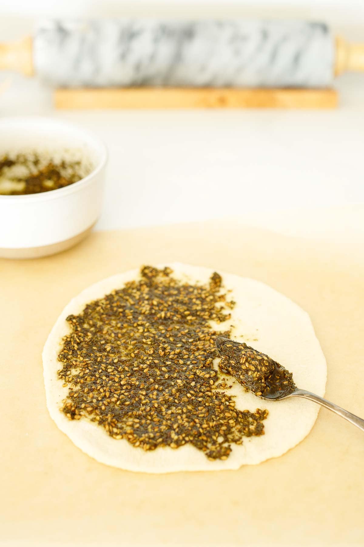 zaatar paste spread out onto manoushe dough.