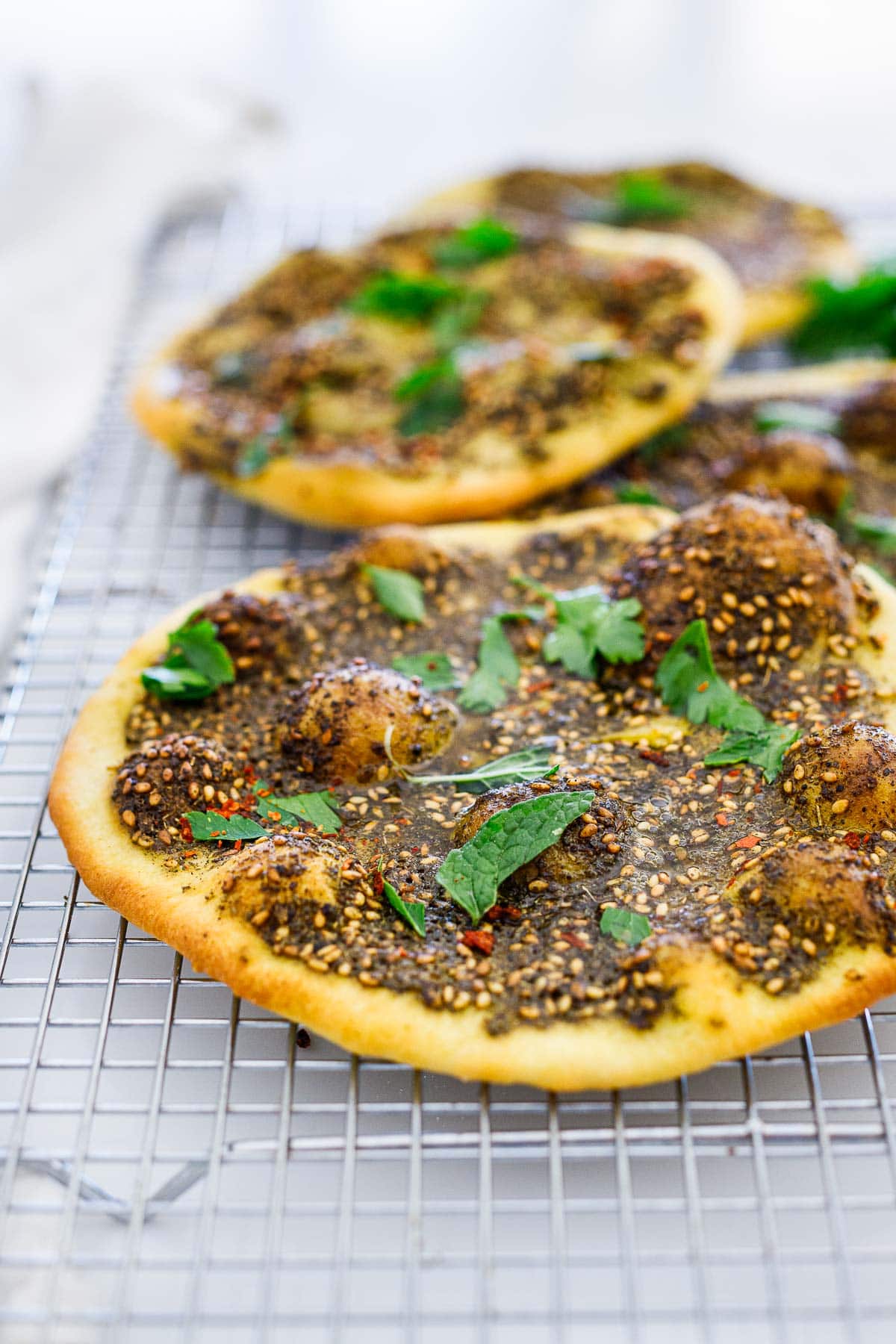 manoushe with zaatar paste and herbs cooling on wire rack.