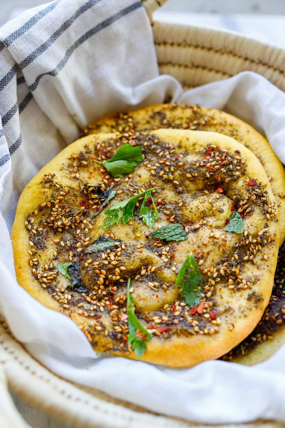 basket of stacked manoushe with fresh herbs.