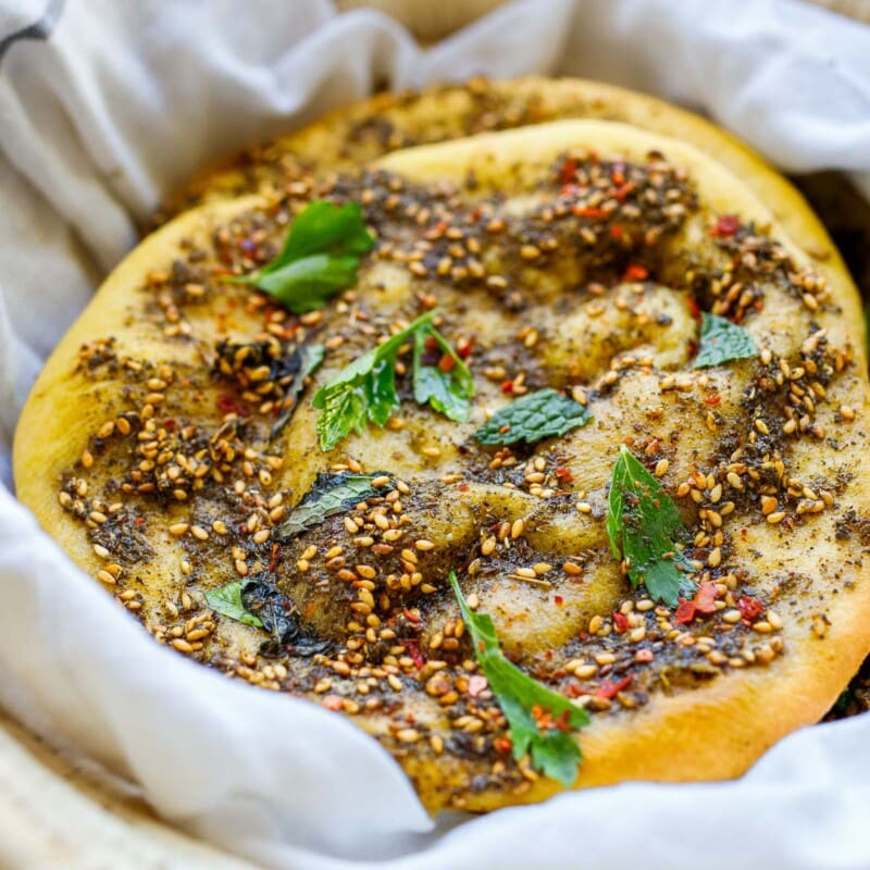 Tender Lebanese flatbread called manoushe is slathered with a mixture of zaatar spice and olive oil, a delicious appetizer or breakfast on the go. Vegan & gluten-free adaptable.