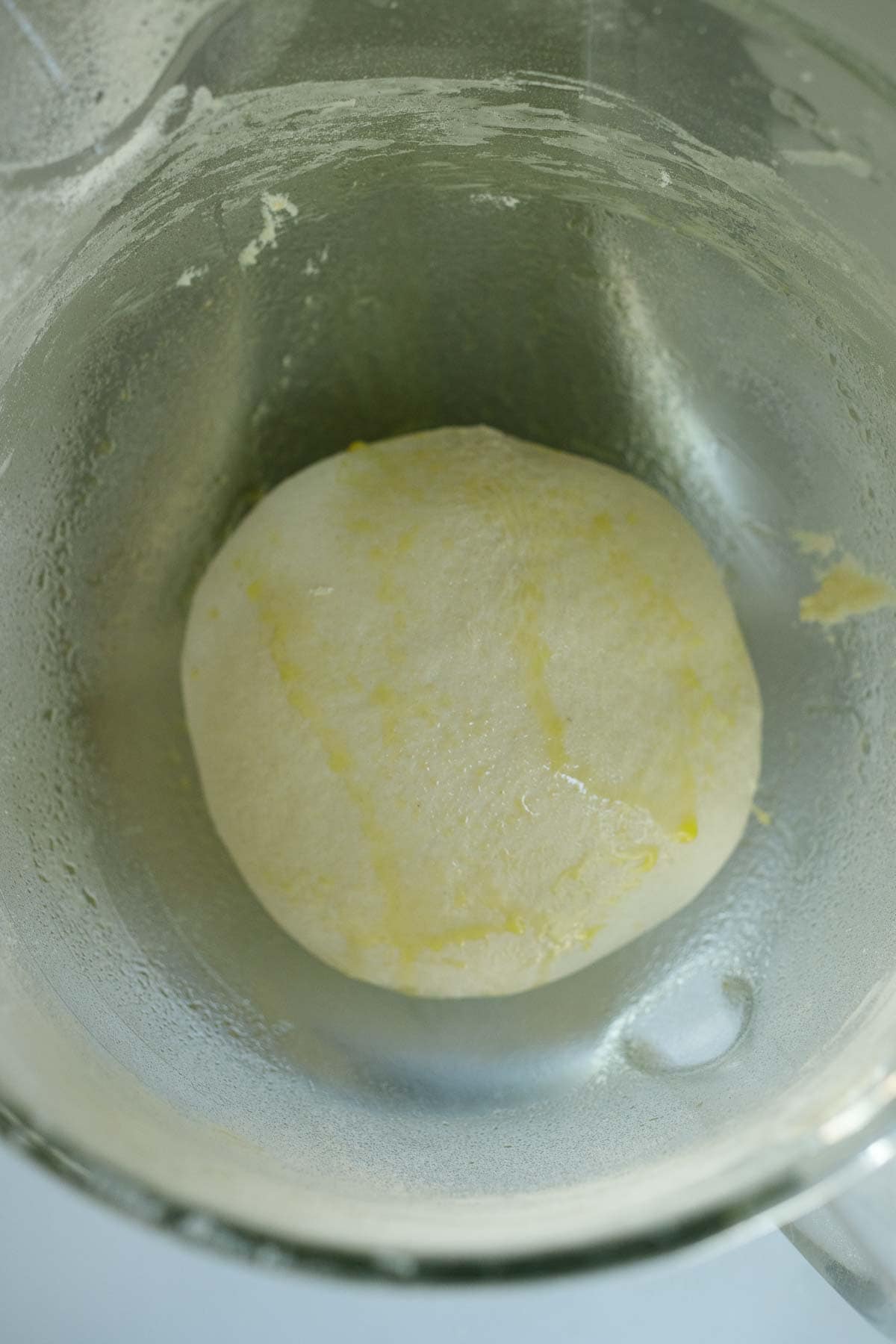 bowl of stand mixer with manoushe dough drizzled with olive oil.