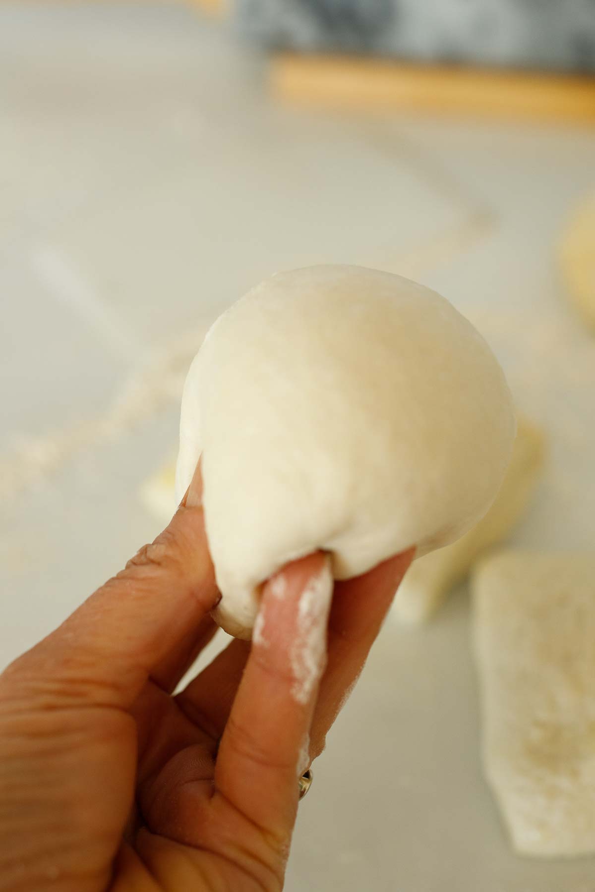 hand holding up rolled ball of manoushe dough.