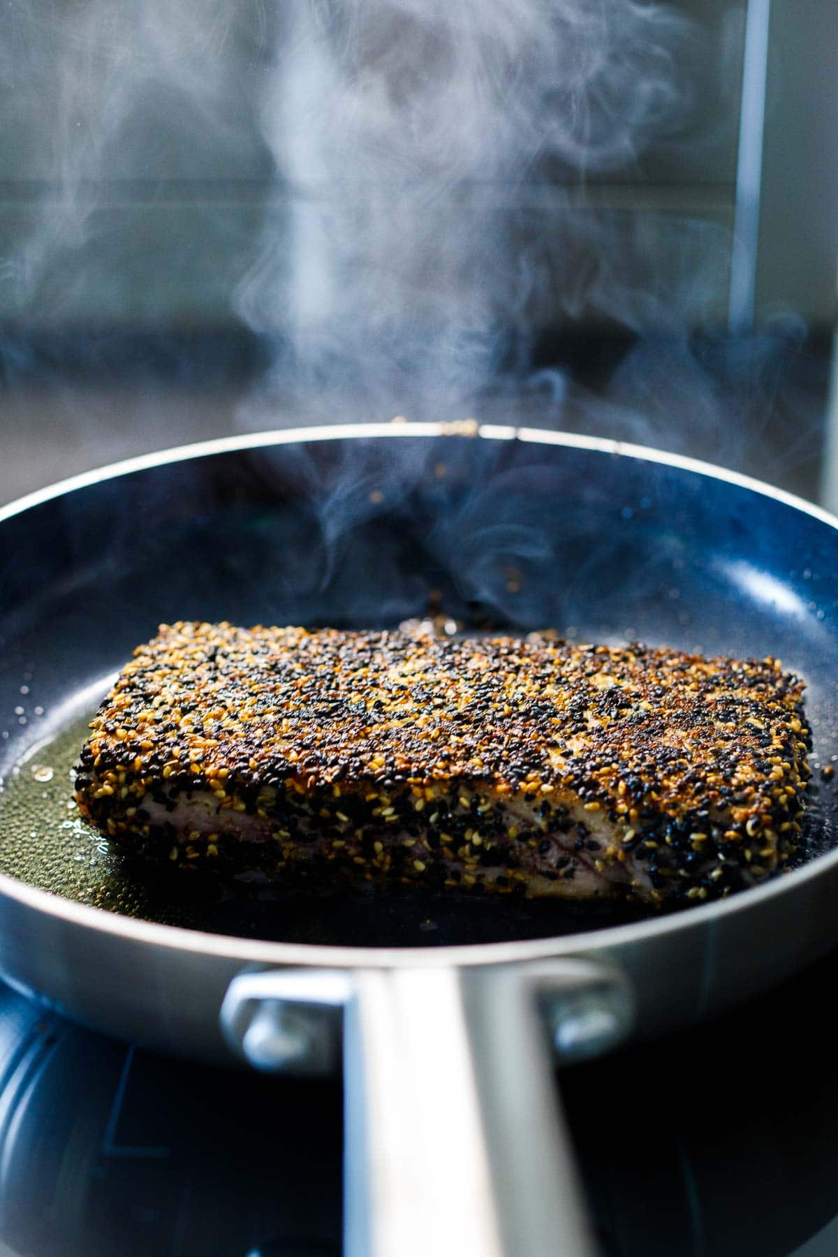 sesame crusted ahi tuna on skillet searing.