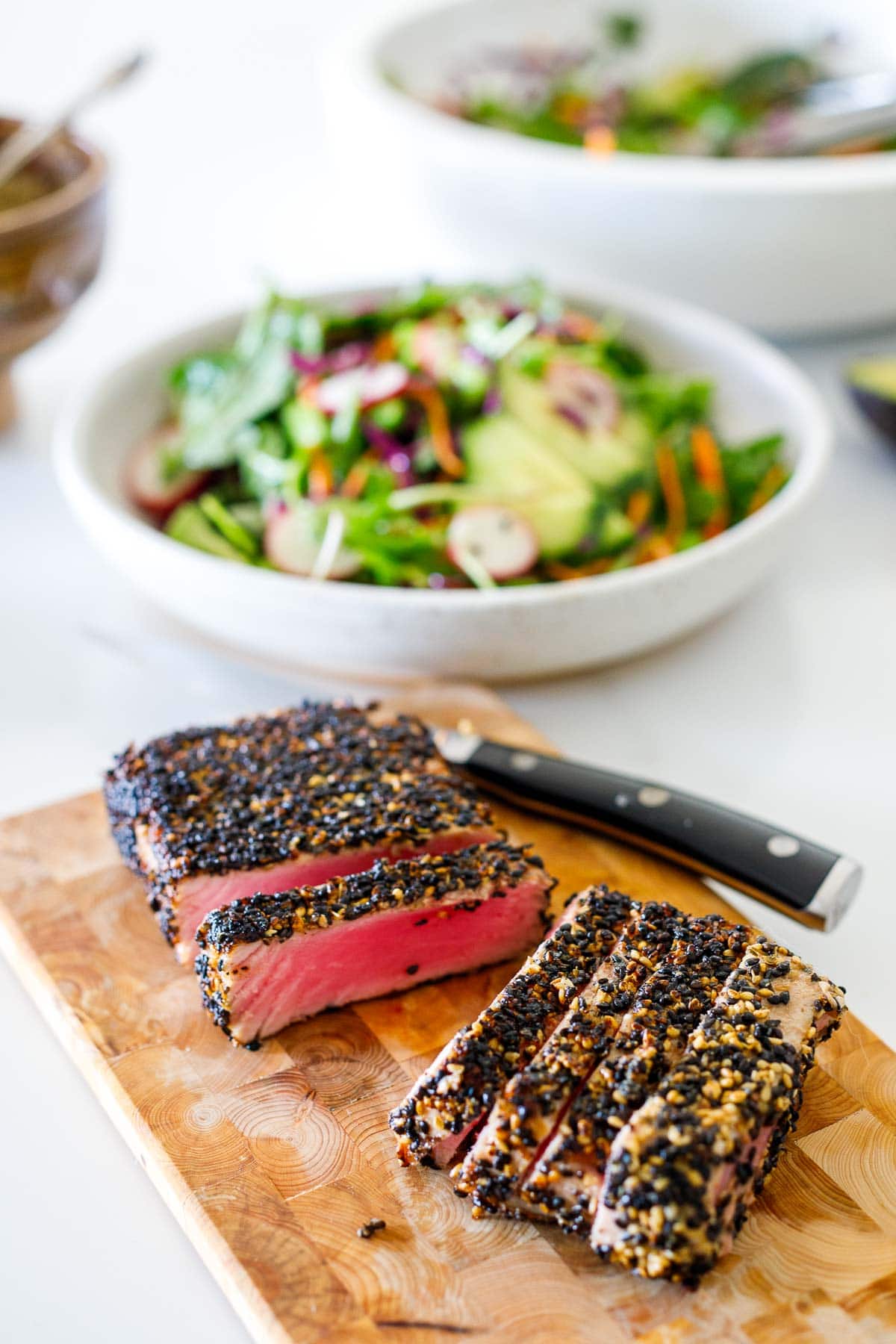 wood cutting board with sliced sesame crusted ahi tuna.