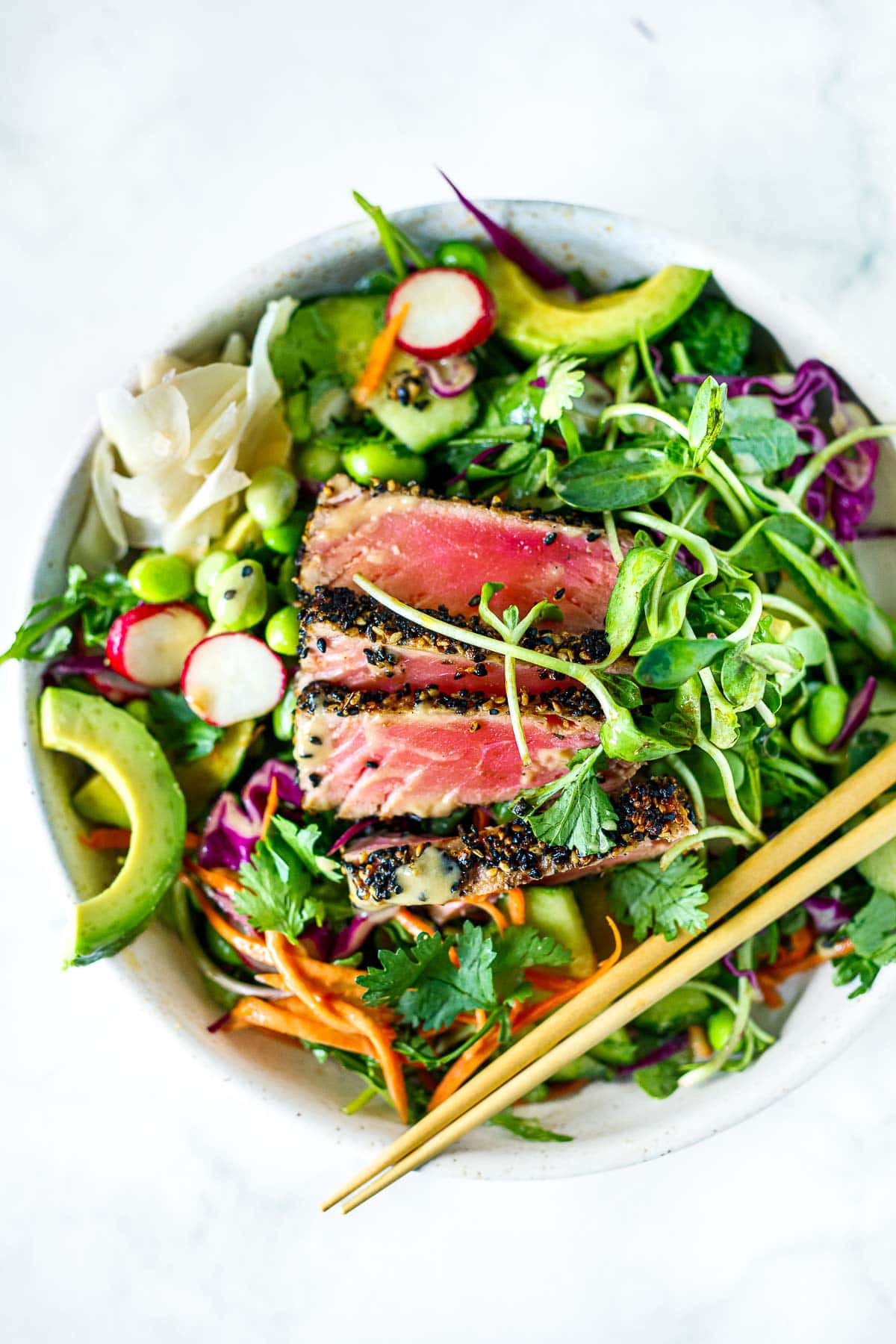 seared ahi tuna salad in bowl with chopsticks on top, served with pickled ginger.