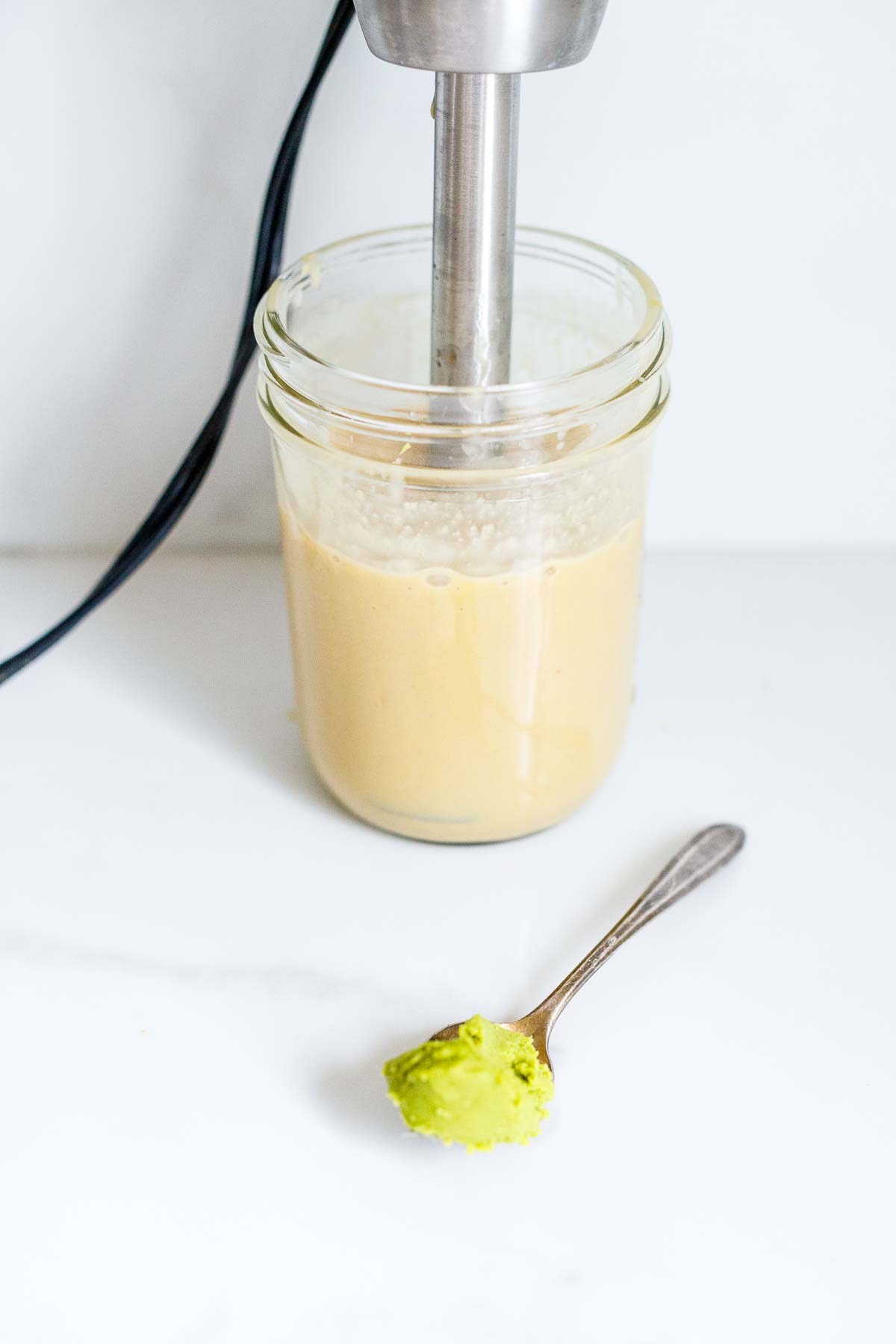 immersion blender blending ginger wasabi dressing with tiny spoon of wasabi. 