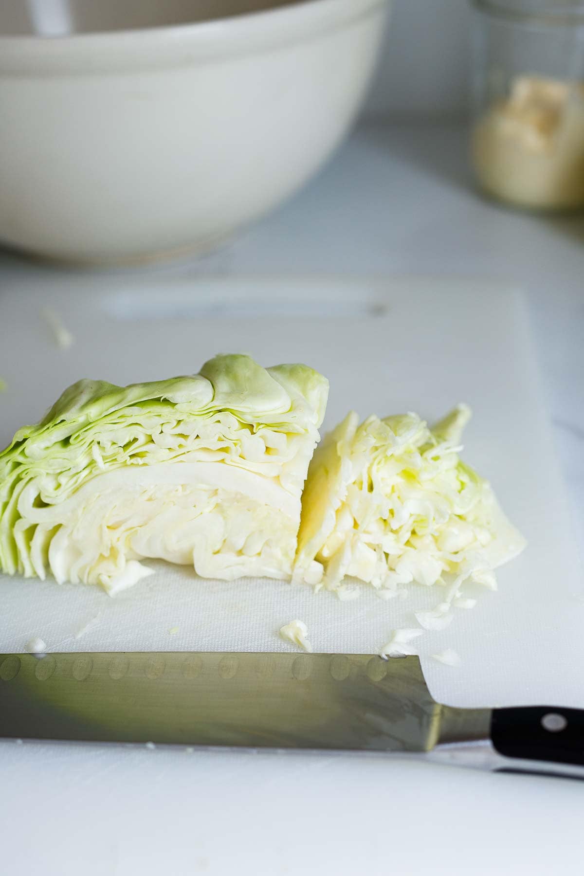 green cabbage thinly sliced on cutting board with sharp knife. 