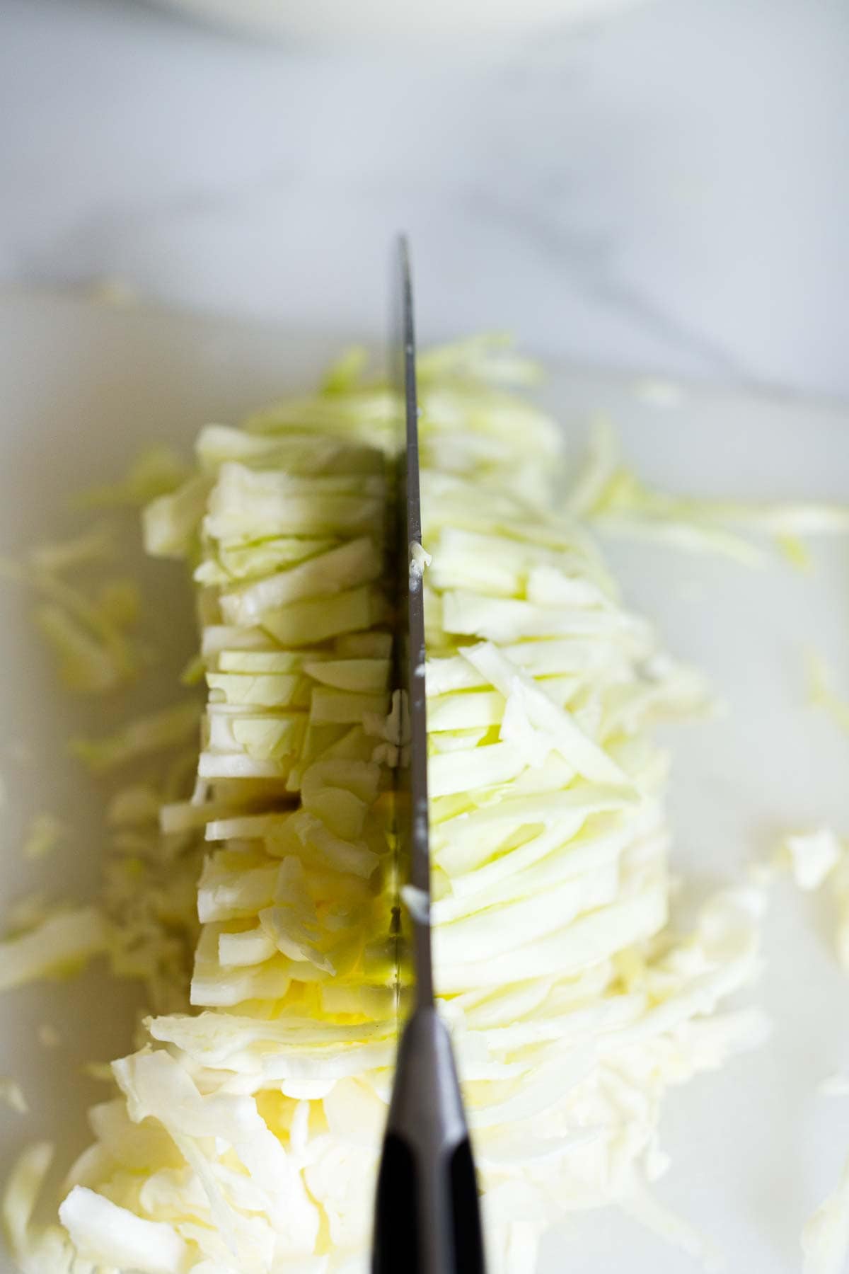 chopping thinly sliced green cabbage with sharp knife. 