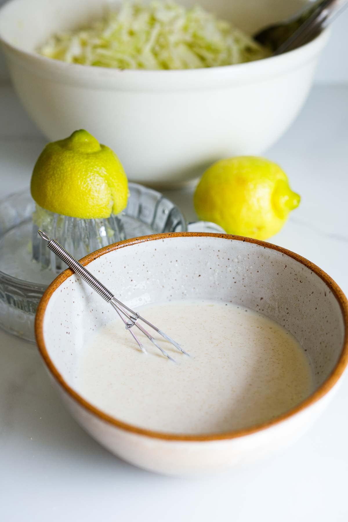 creamy coleslaw dressing in small bowl with whisk. 